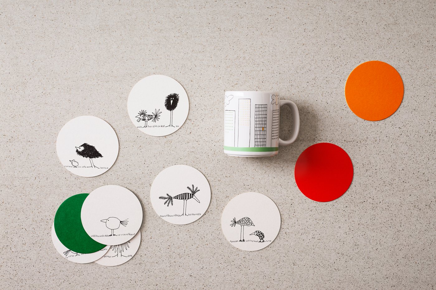An aerial view of coasters and a mug featuring graphic drawings.