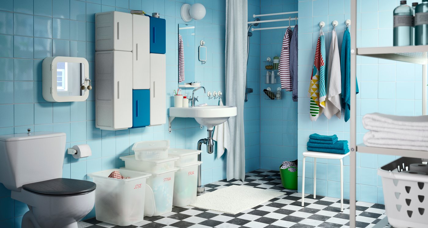 A family bathroom with turquoise tiled walls and lots of storage and towels, etc., hanging from the walls.
