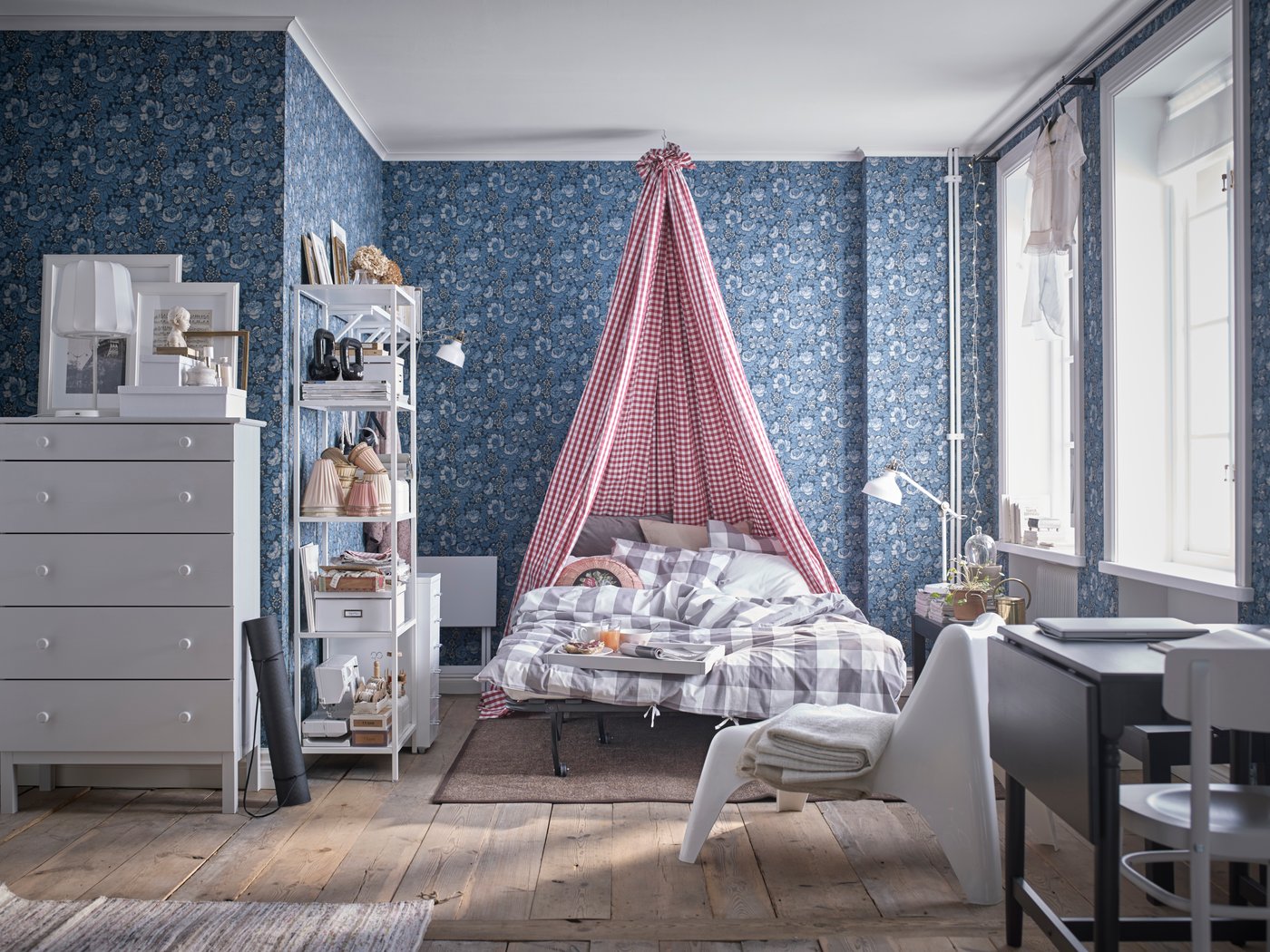 A bed with a red and white canopy in a blue floral bedroom.