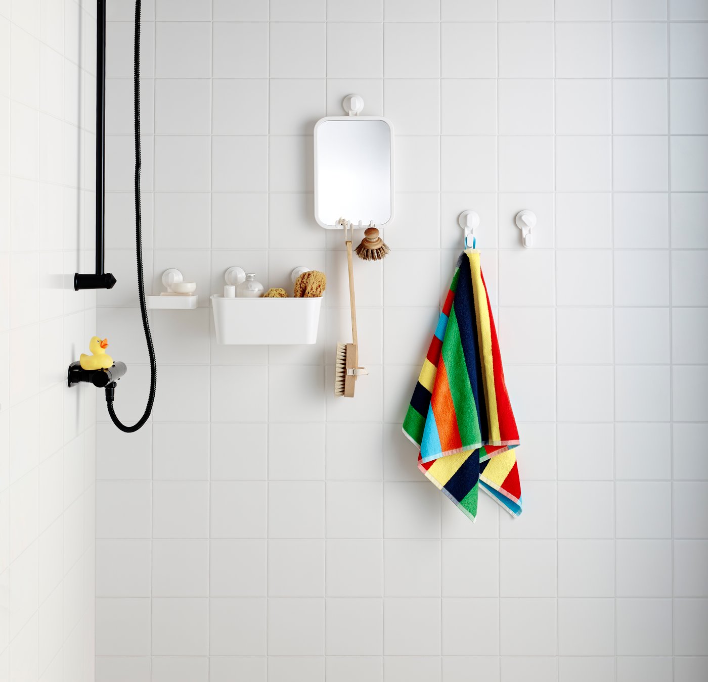 A  colourful striped towel hangs from a STUGVIK hook on a white tiled bathroom wall.
