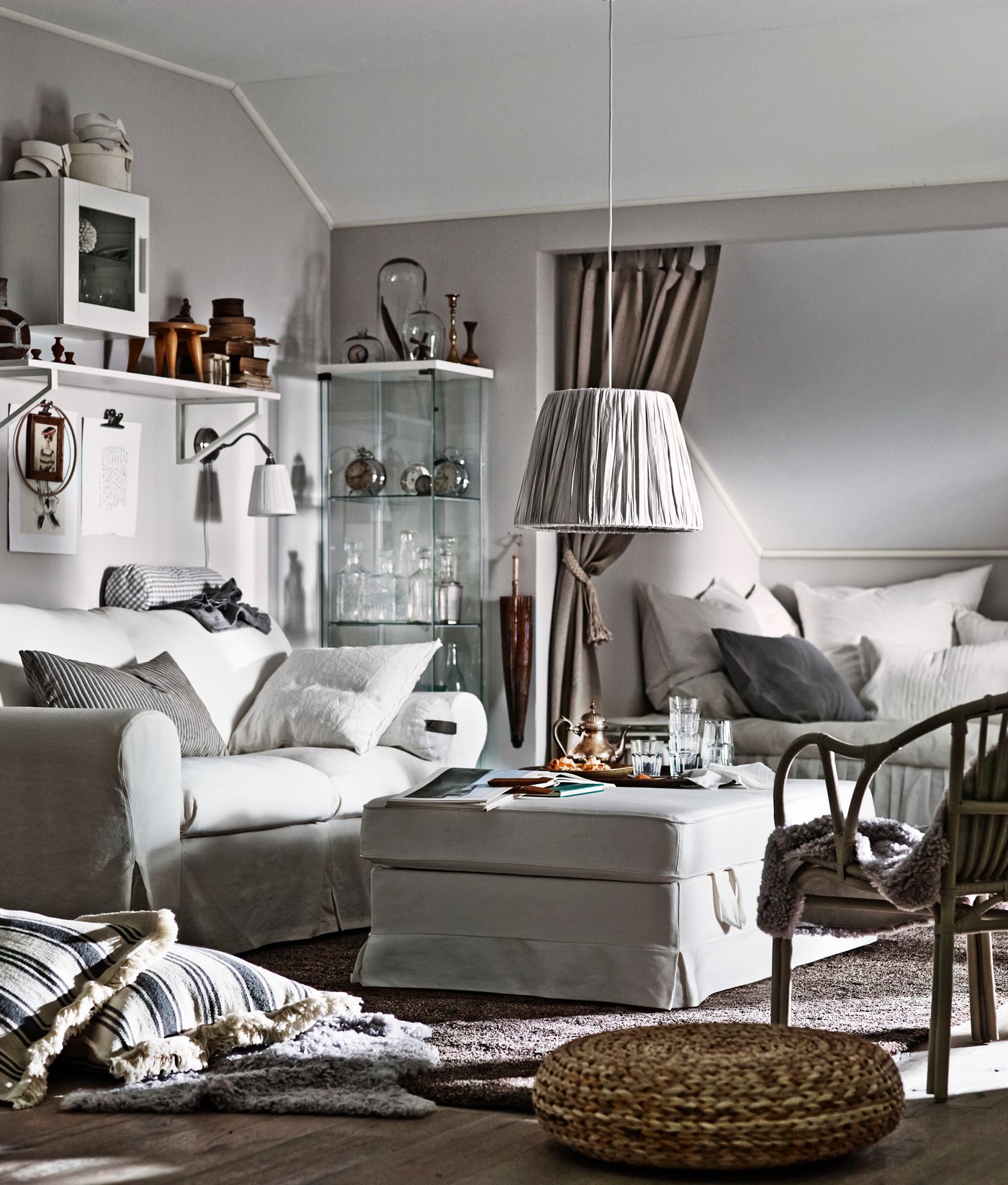 A grey living room with a grey sofa, lamp and footstool.