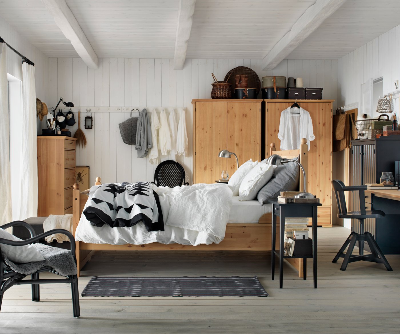 A rustic style bedroom with ceiling beams, natural coloured wood furniture and a patchwork quilt on the bed.