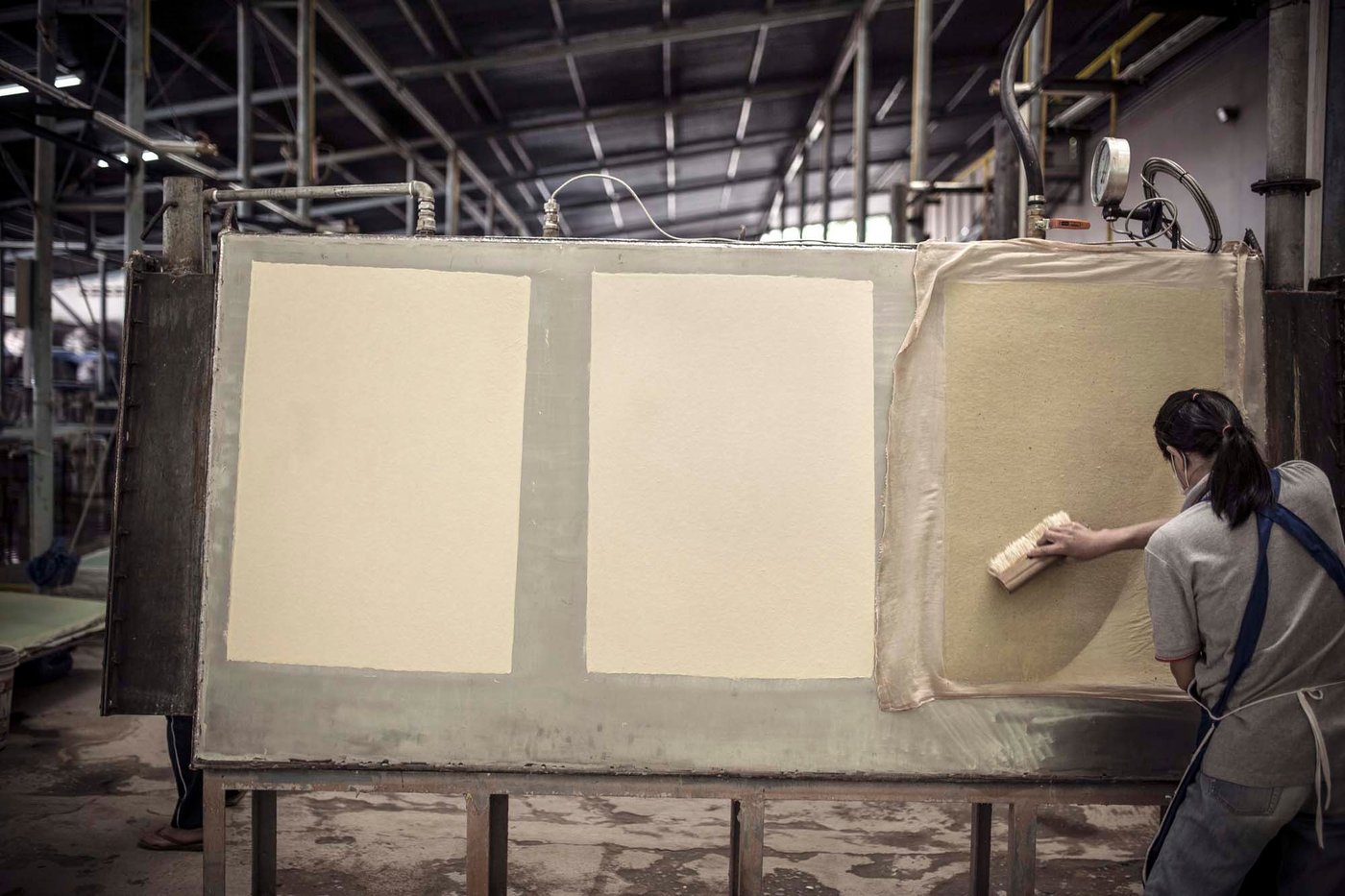 A woman makes paper on a large board.
