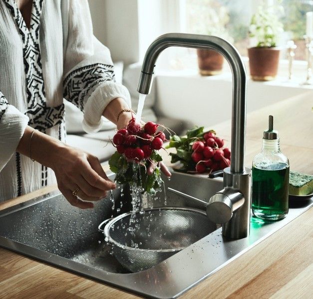 A person washes a bunch of radishes under a running tap. 