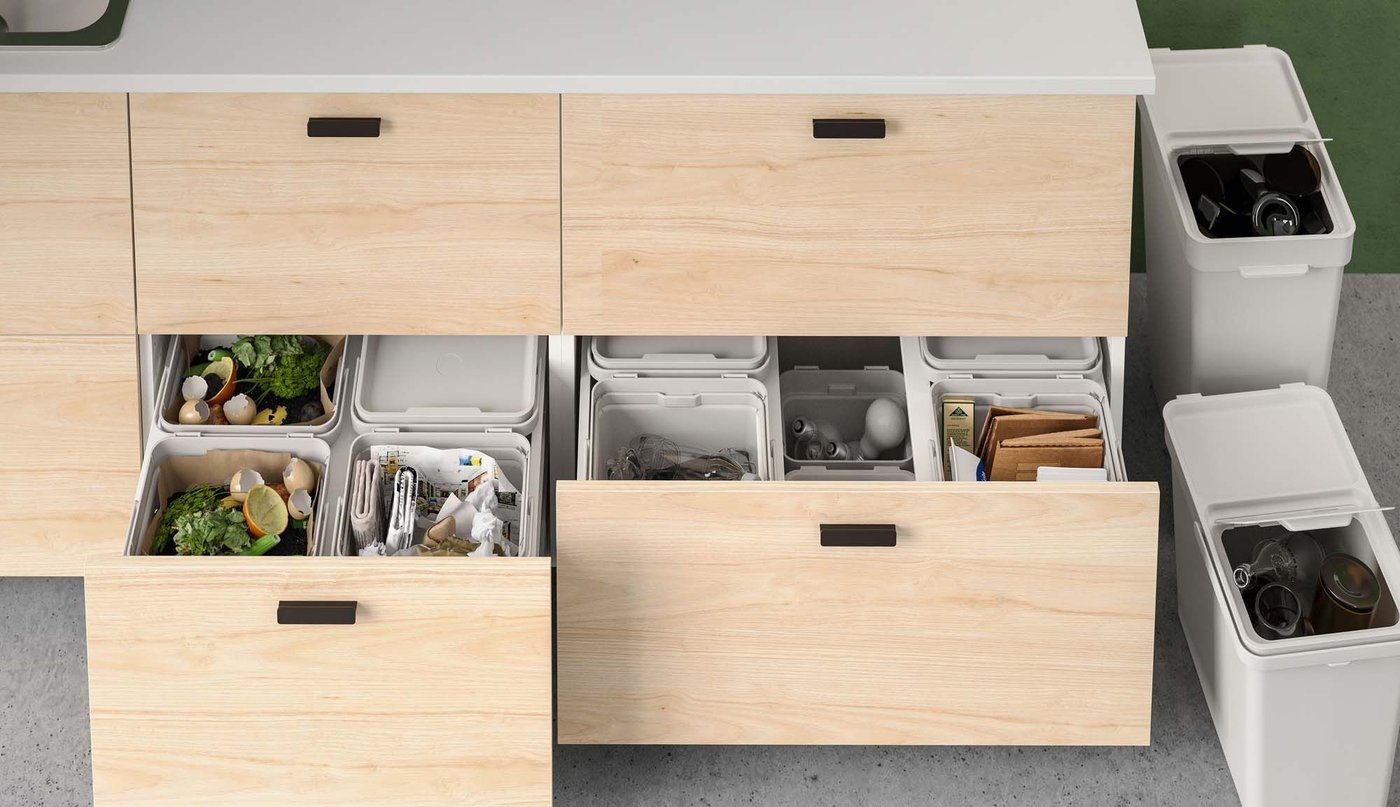 Open drawers in the bottom of a kitchen island unit reveal a system of waste recycling bins.