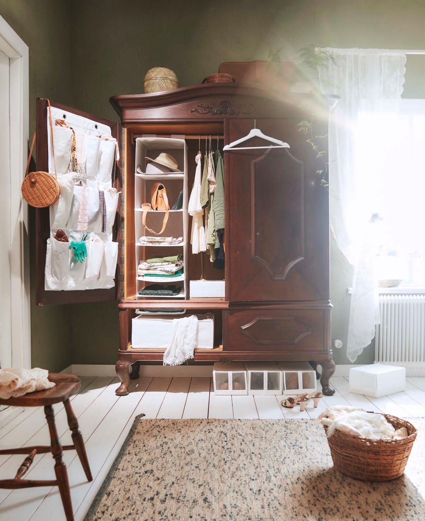 A wooden wardrobe in a bedroom. The doors are open, revealing hanging wardrobe organisers.