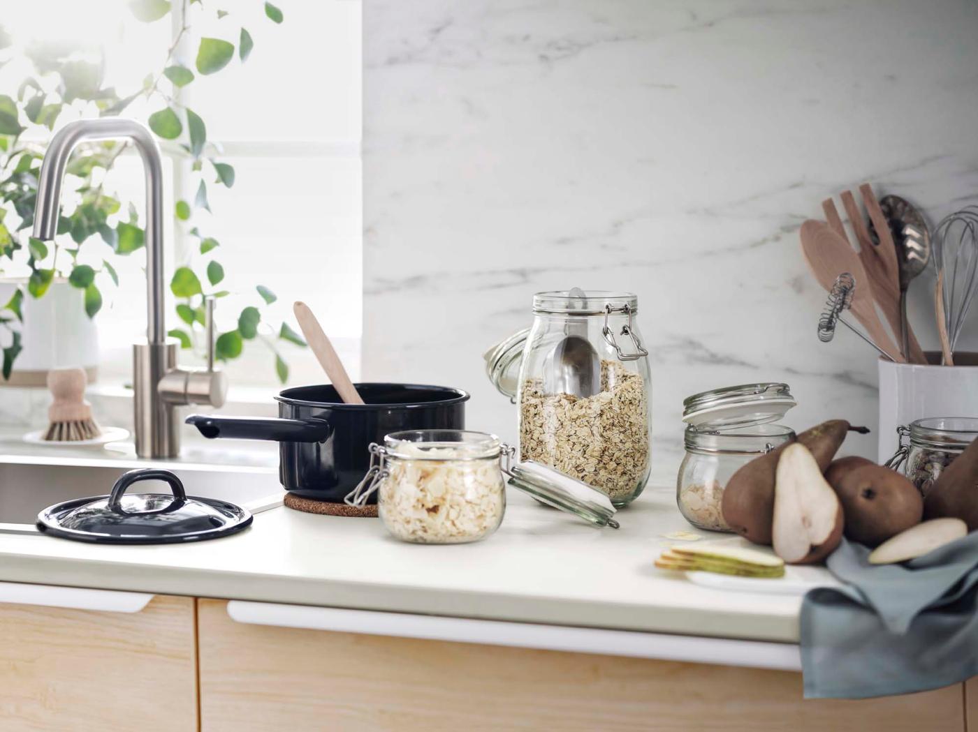Glass storage jars and a saucepan on a light kitchen countertop.