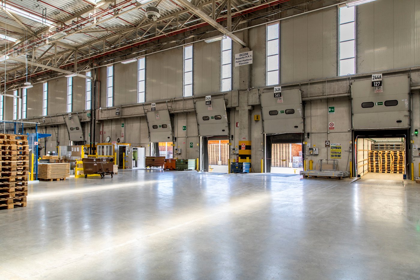 Interior view of a massive distribution centre with open loading bays letting in sunlight.