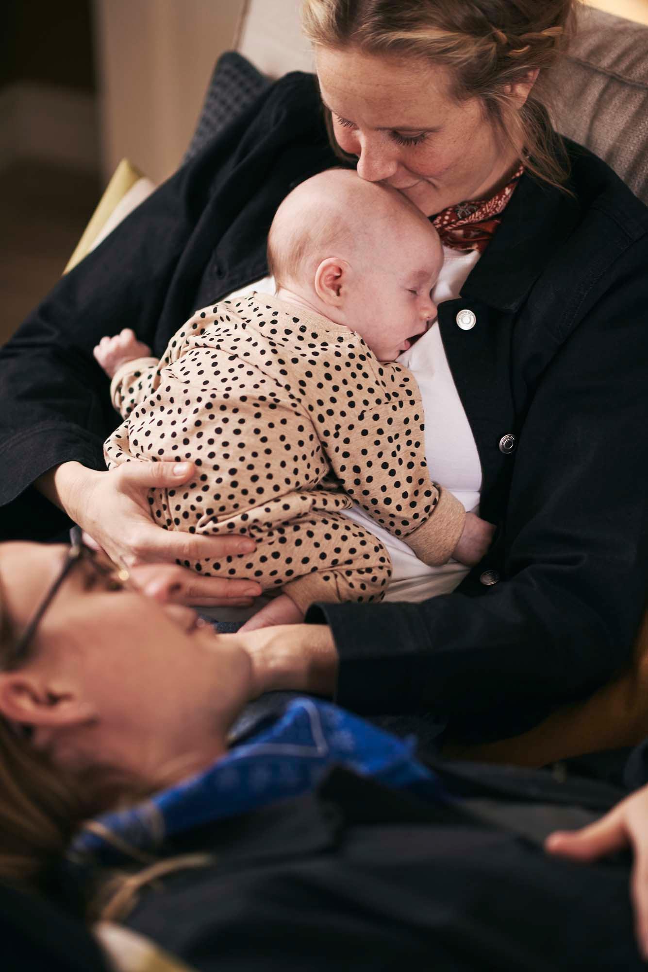 A person kisses the head of a baby asleep in their arms.