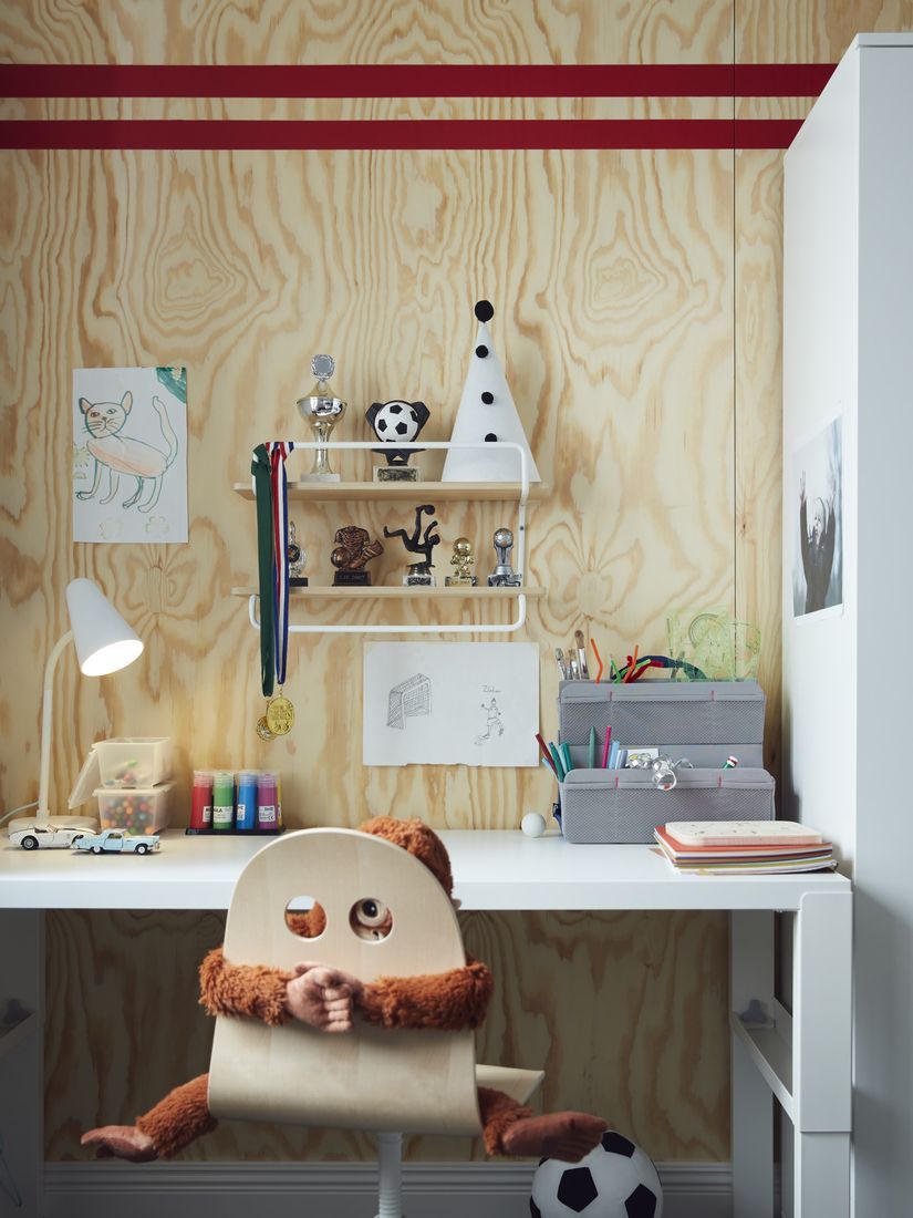 Children's desk against a plywood wall, with a SPORTSLIG wall shelf for trophies mounted directly above.