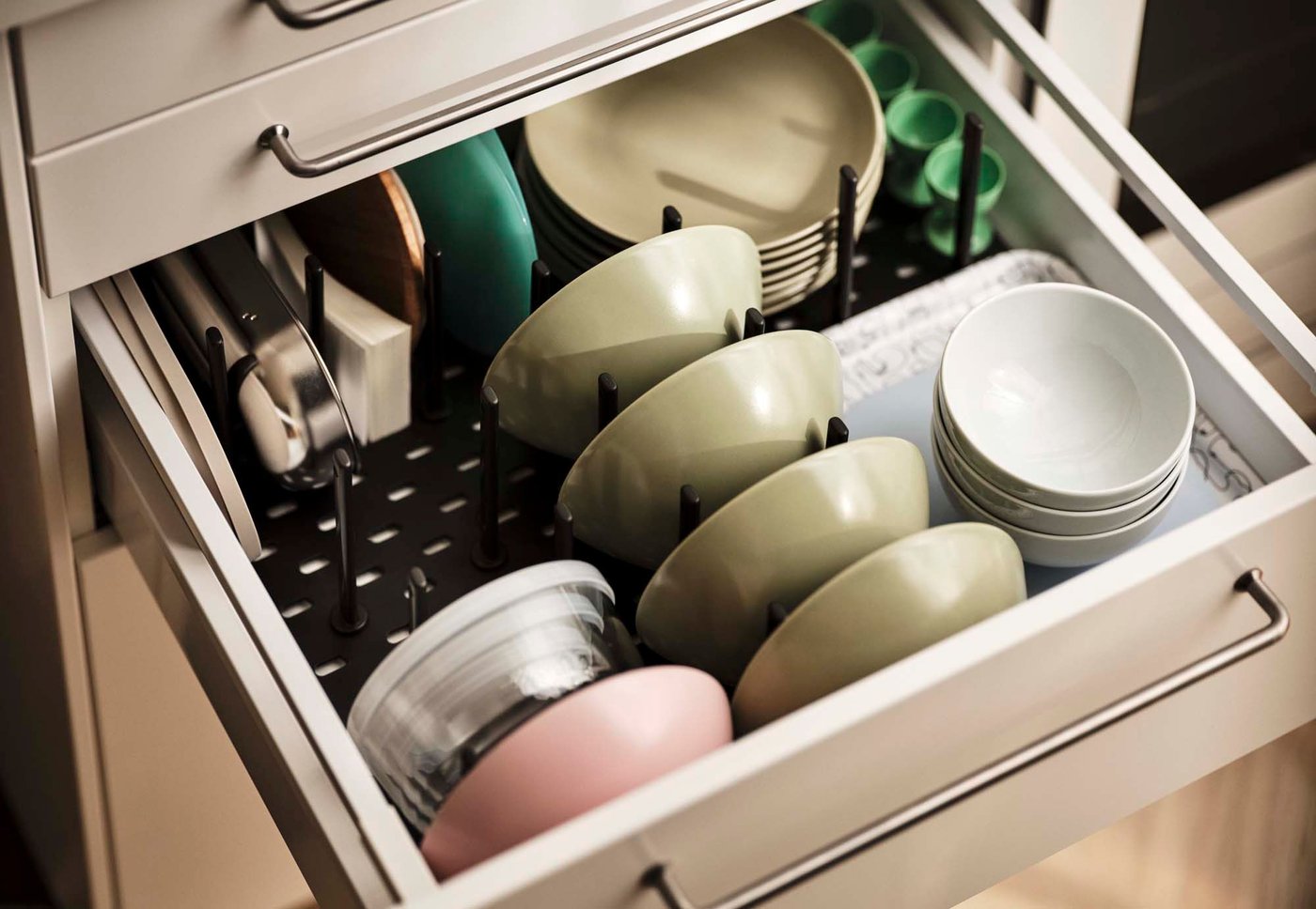 An open kitchen drawer with bowls and plates arranged in an UPPDATERA pegboard drawer organiser.