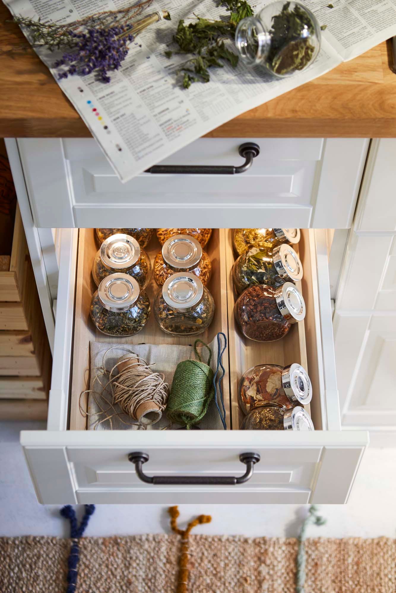 A drawer filled with herbs in jars and some gardening twine.