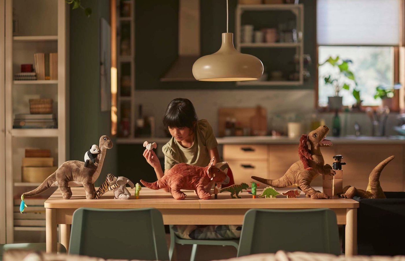 A girl leans on a table, playing with toy dinosaurs and animals.
