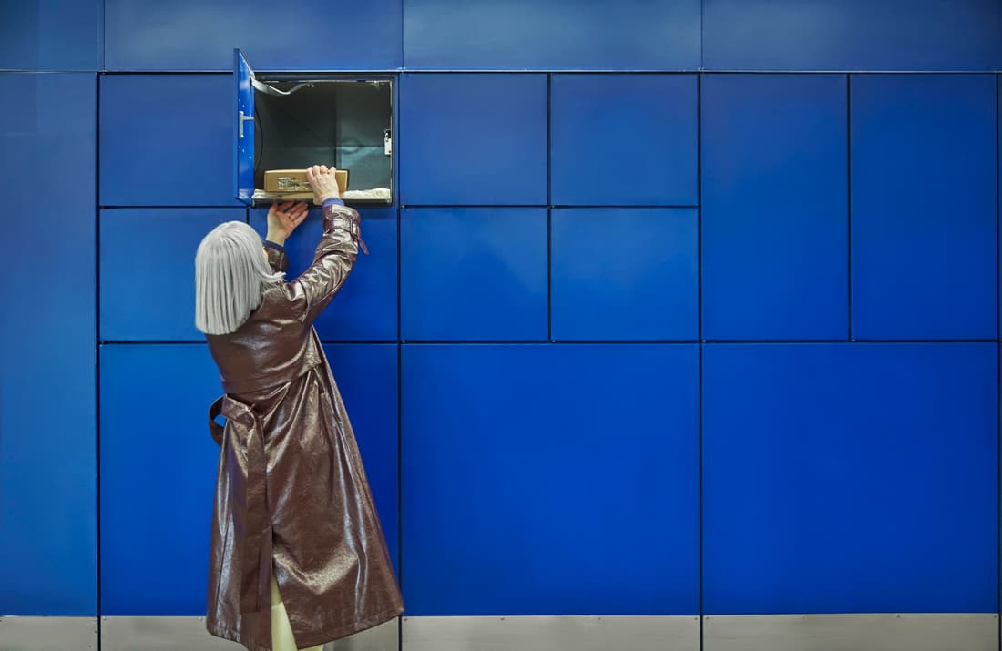 A person taking a package out of a blue locker.