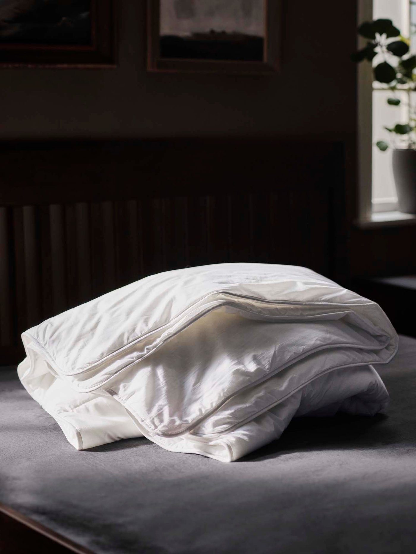 A SMÅSPORRE duvet is folded on a bed with a dark background.