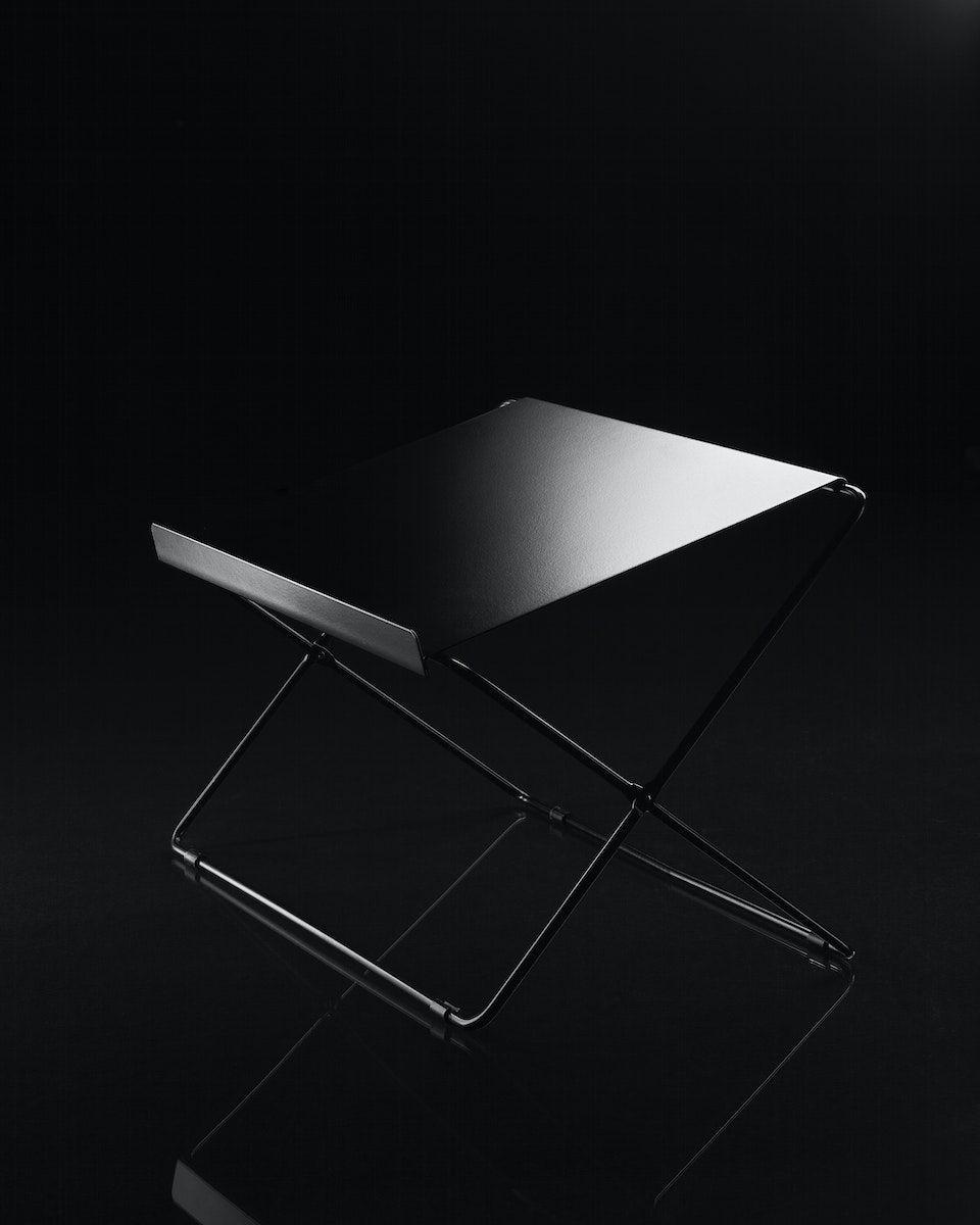 Black OBEGRÄNSAD laptop stand on a black background.