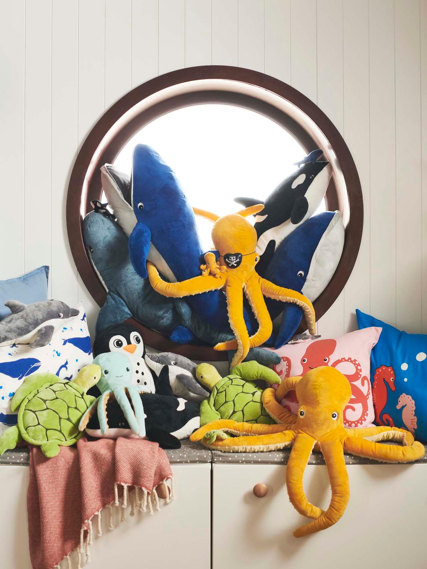 A collection of marine inspired toys on and below the windowsill of a round window.