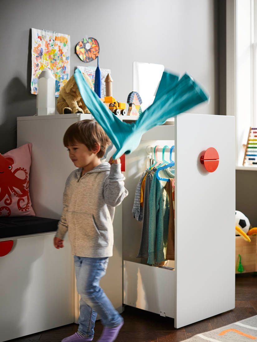A child grabs an item of clothing from the open drawer of a SMÅSTAD storage combination. 
