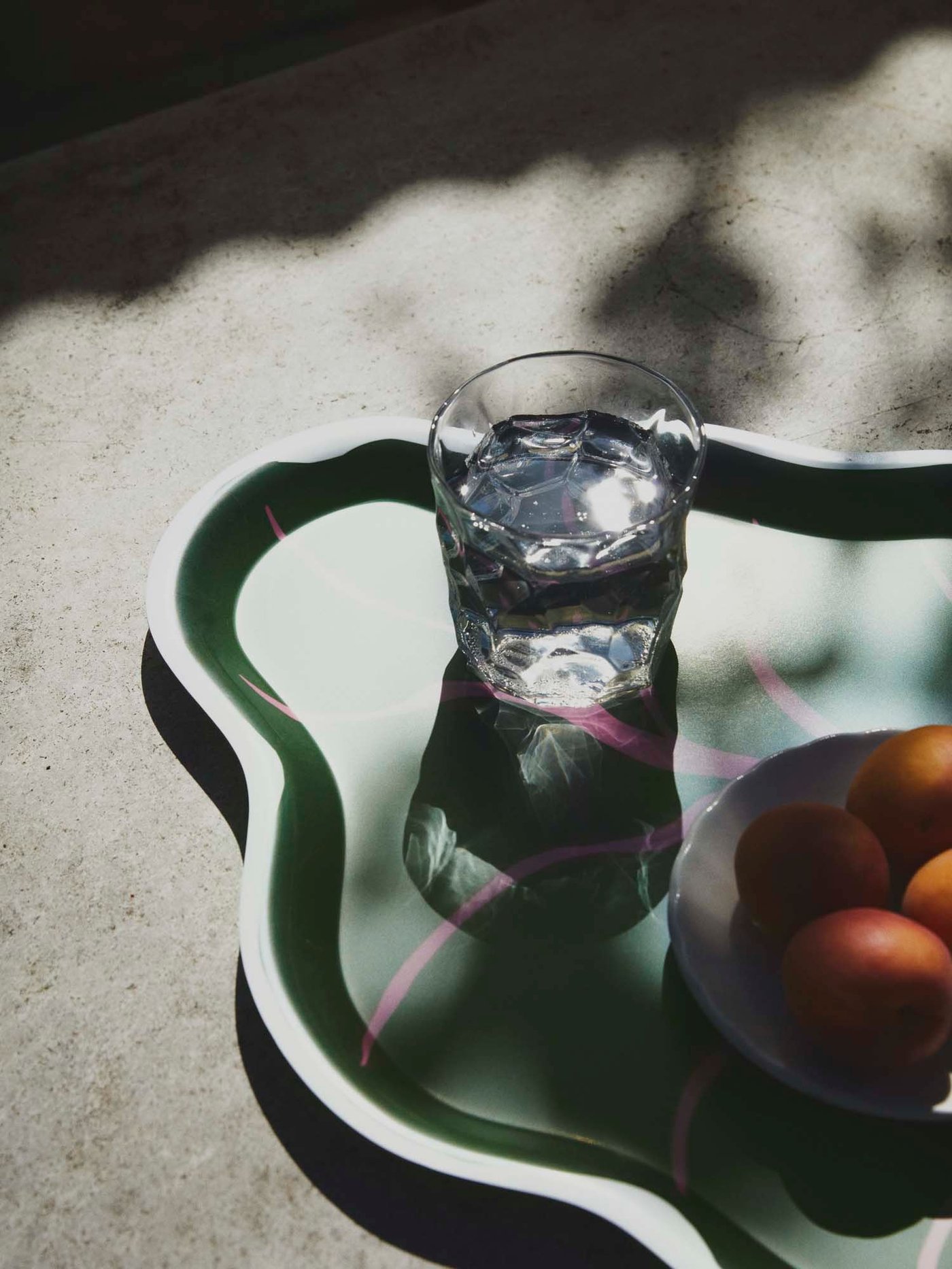 A glass on a curved tray with shadows.