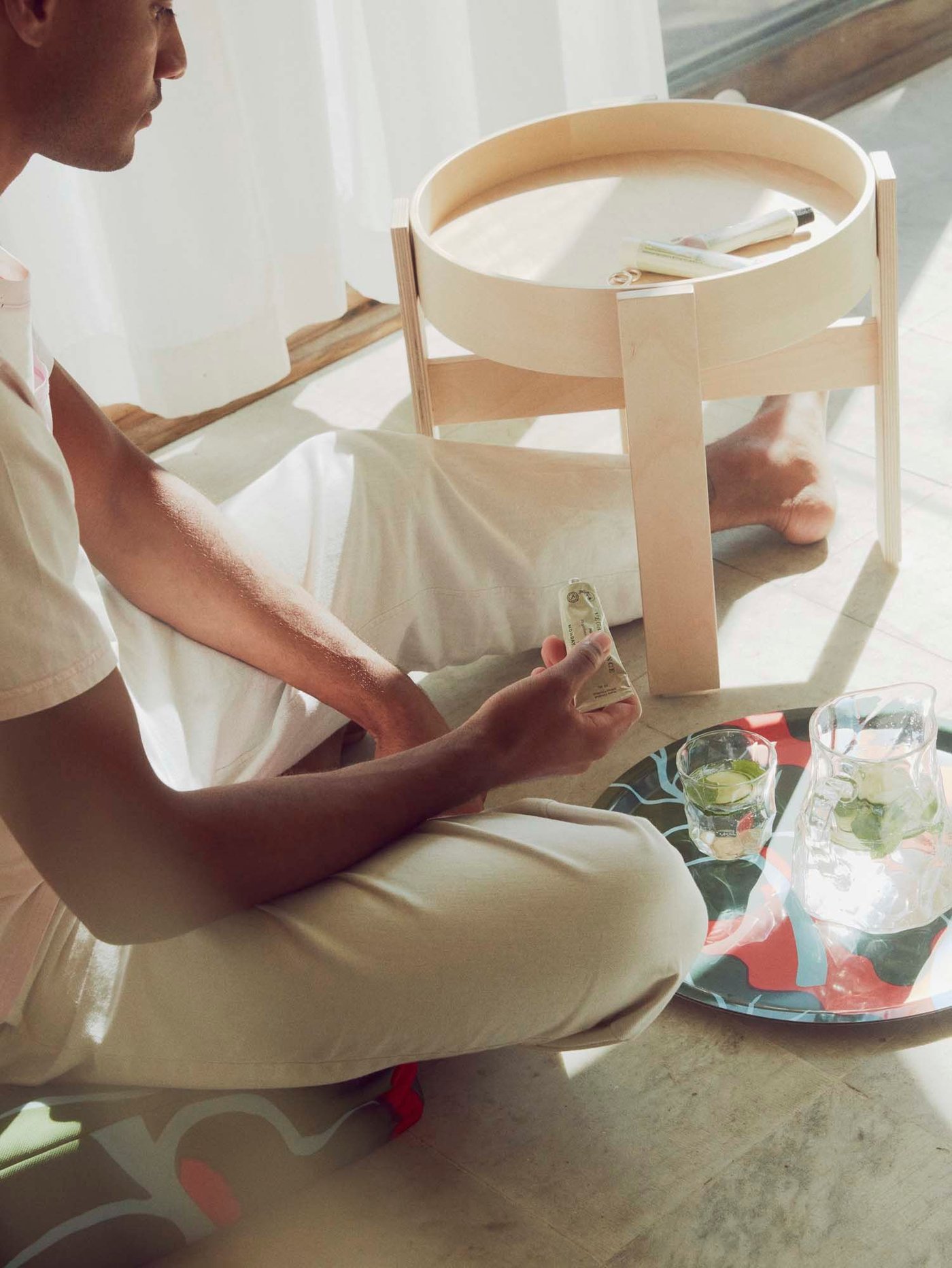 A man sits on the floor next to a table and tray.