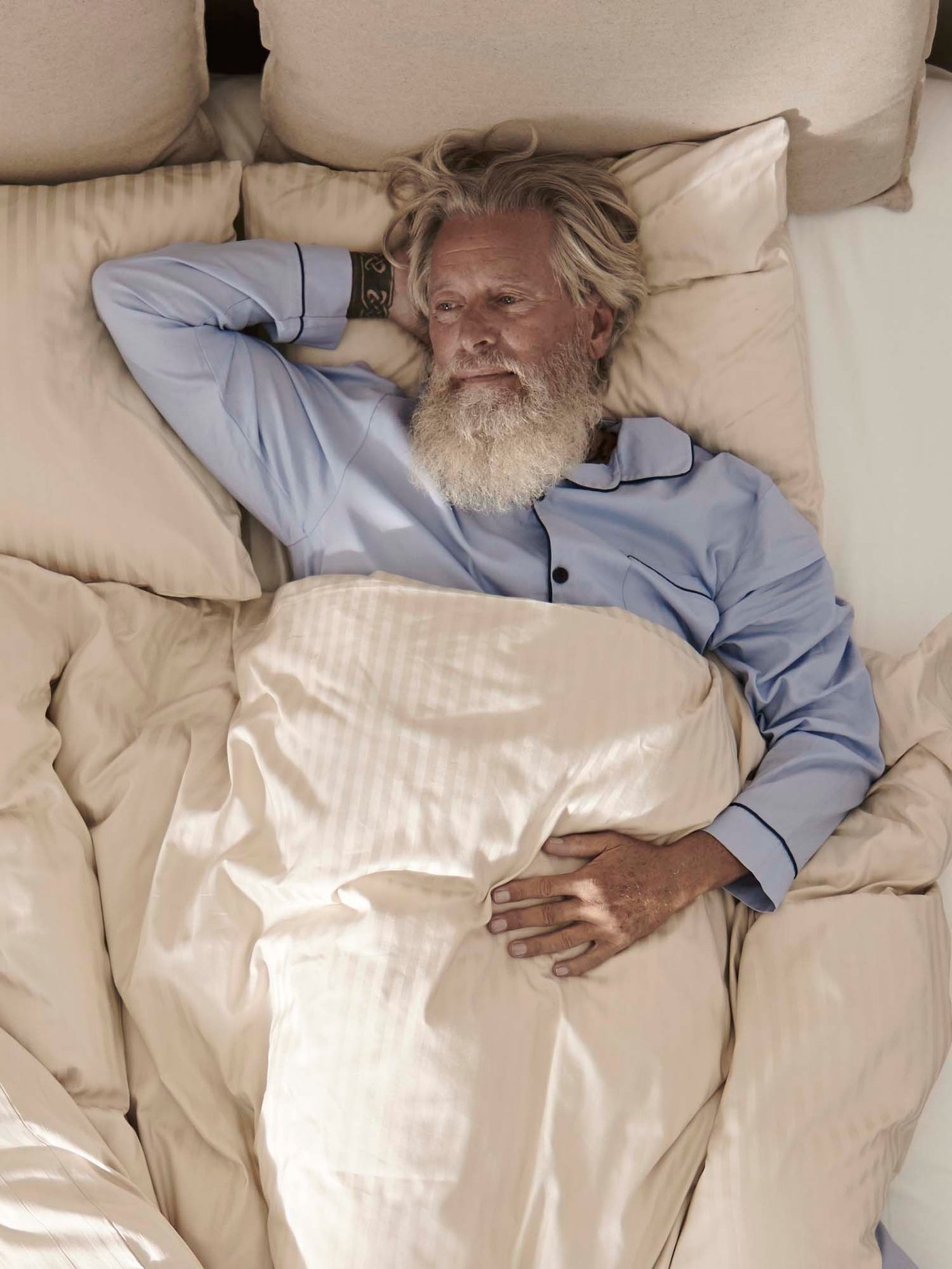 Aerial view of a person wearing blue pyjamas lying in a bed with white bed linen.