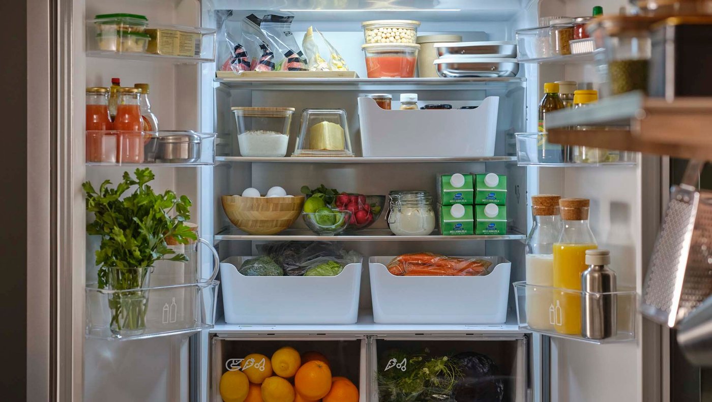 An open VINTERKALL French door fridge/freezer filled with food neatly organised in an assortment of food containers.