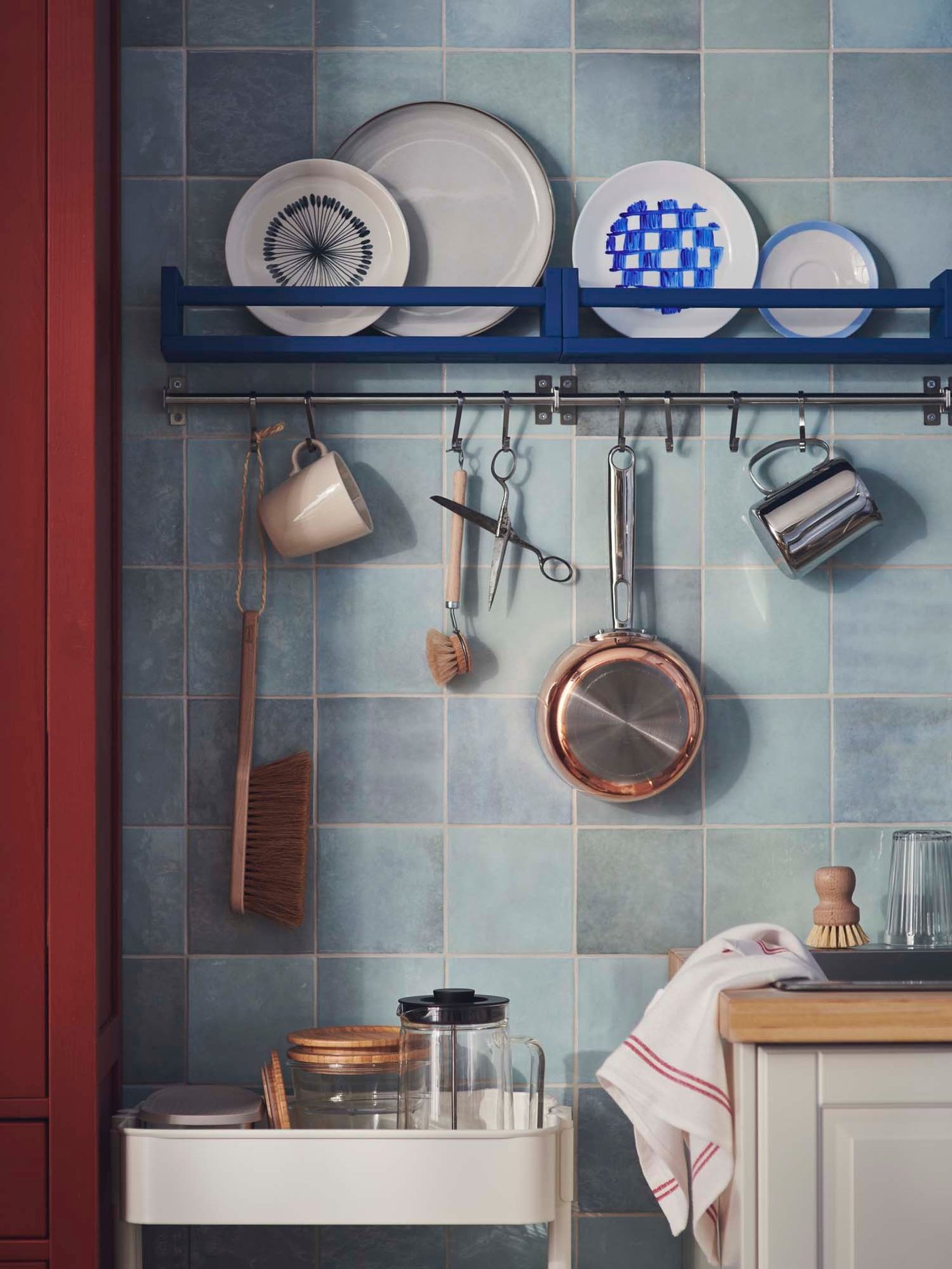 A kitchen with items hanging from stainless steel KUNGSFORS hooks on a KUNGSFORS rail with plates displayed above.