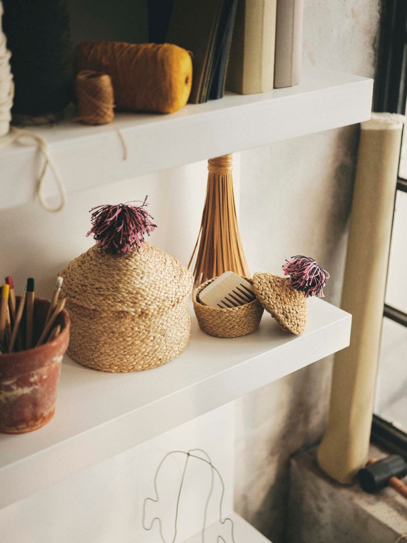 Baskets and pen pots on white shelves.