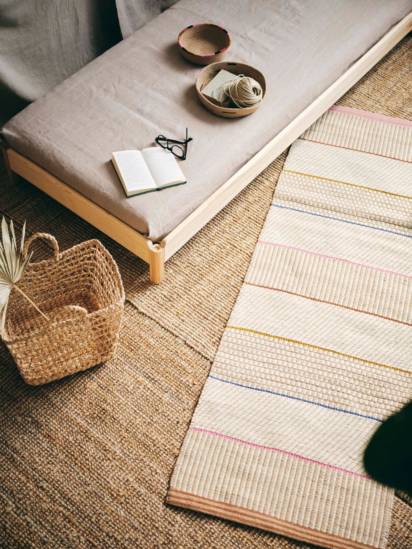 A handmade rug, a bench and a bag placed on a larger rug.