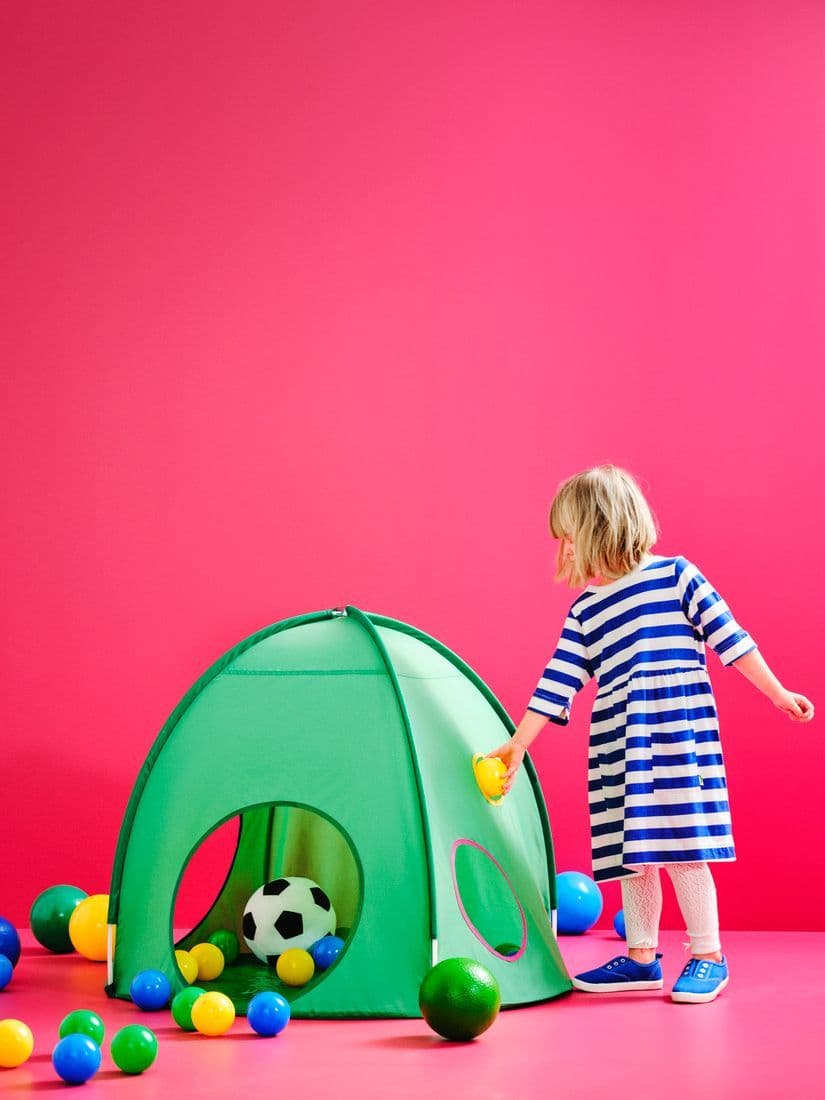 A child plays with in a bright pink room near a green DVÄRGMÅS tent.
