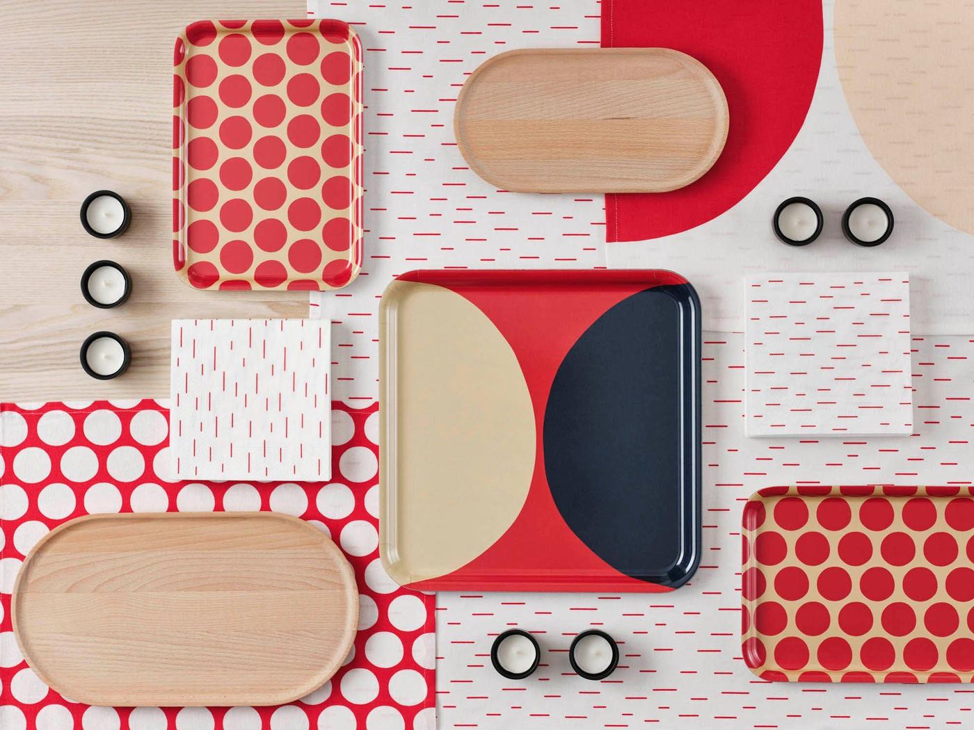 Top view of a table surface covered in boldly patterned paper, trays, napkins and tea candles.