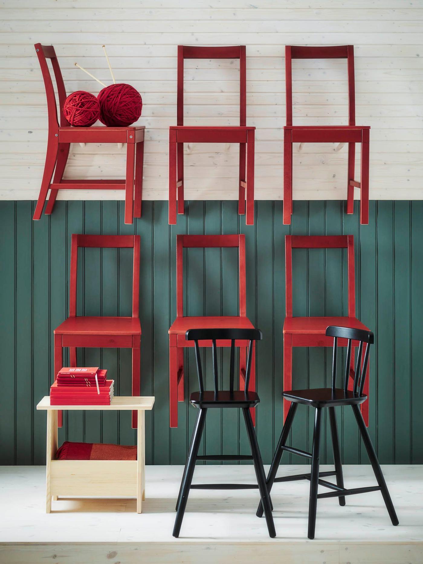 Six red PINNTORP chairs, mounted on a green-panelled wall. A bench and two black children's are in the foreground.