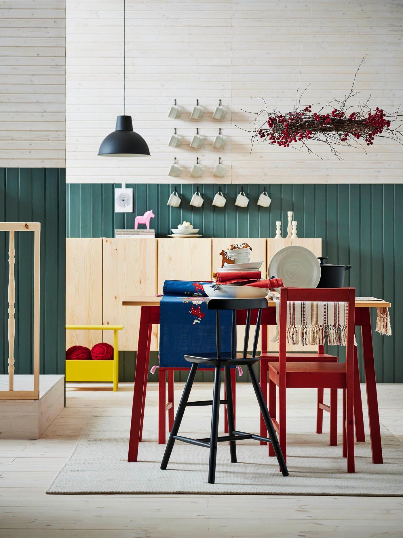 Colourful farmhouse-style dining area with green-panelled walls, pine IVAR cabinets and a red PINNTORP dining suite.