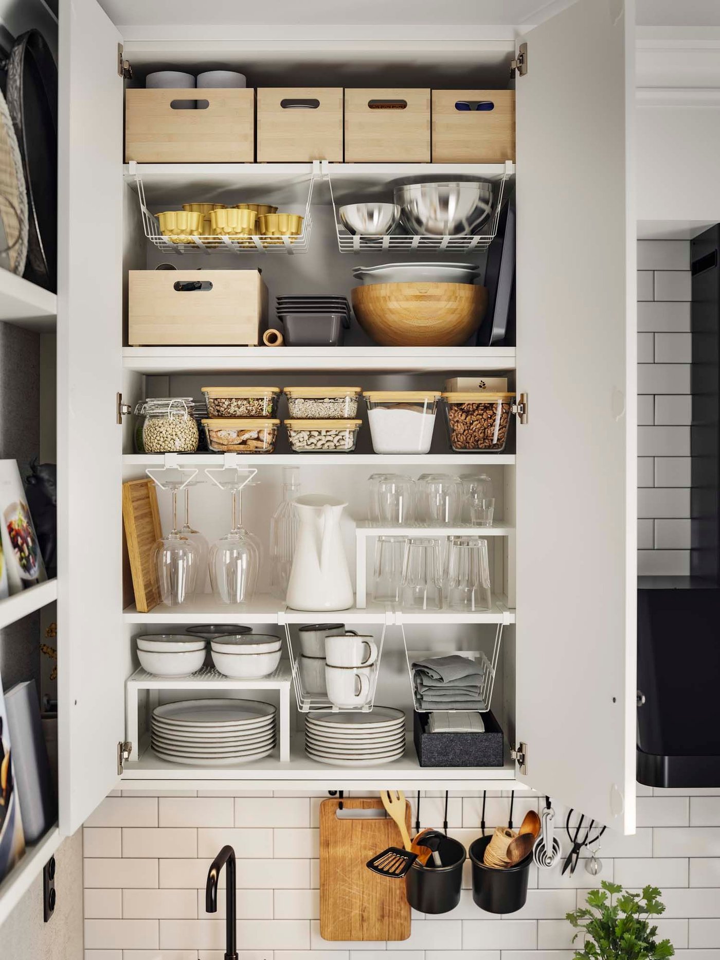 An open cupboard revealing plates, glasses and containers in a kitchen.