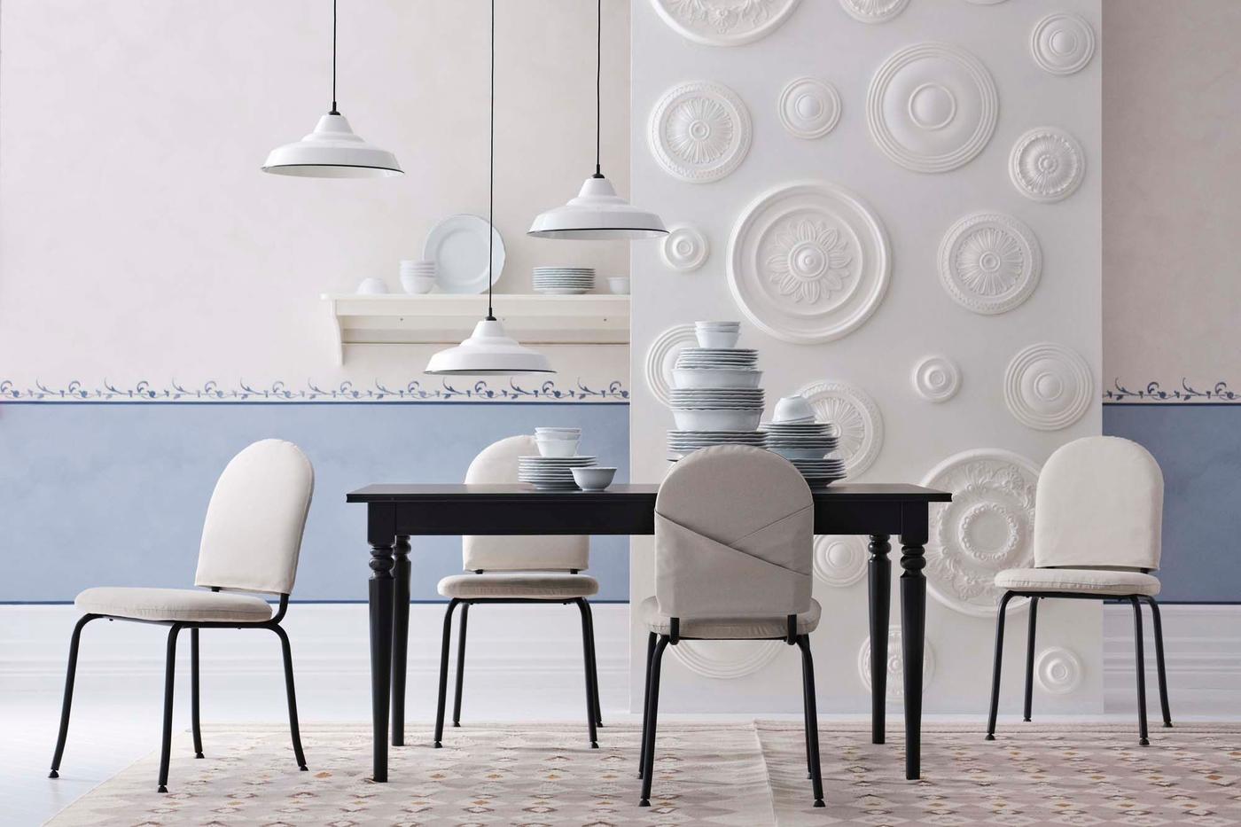 A black table surrounded by cream EBBALYCKE chairs, are placed under hanging white TRETTIOEN lamps in a blue and white room.