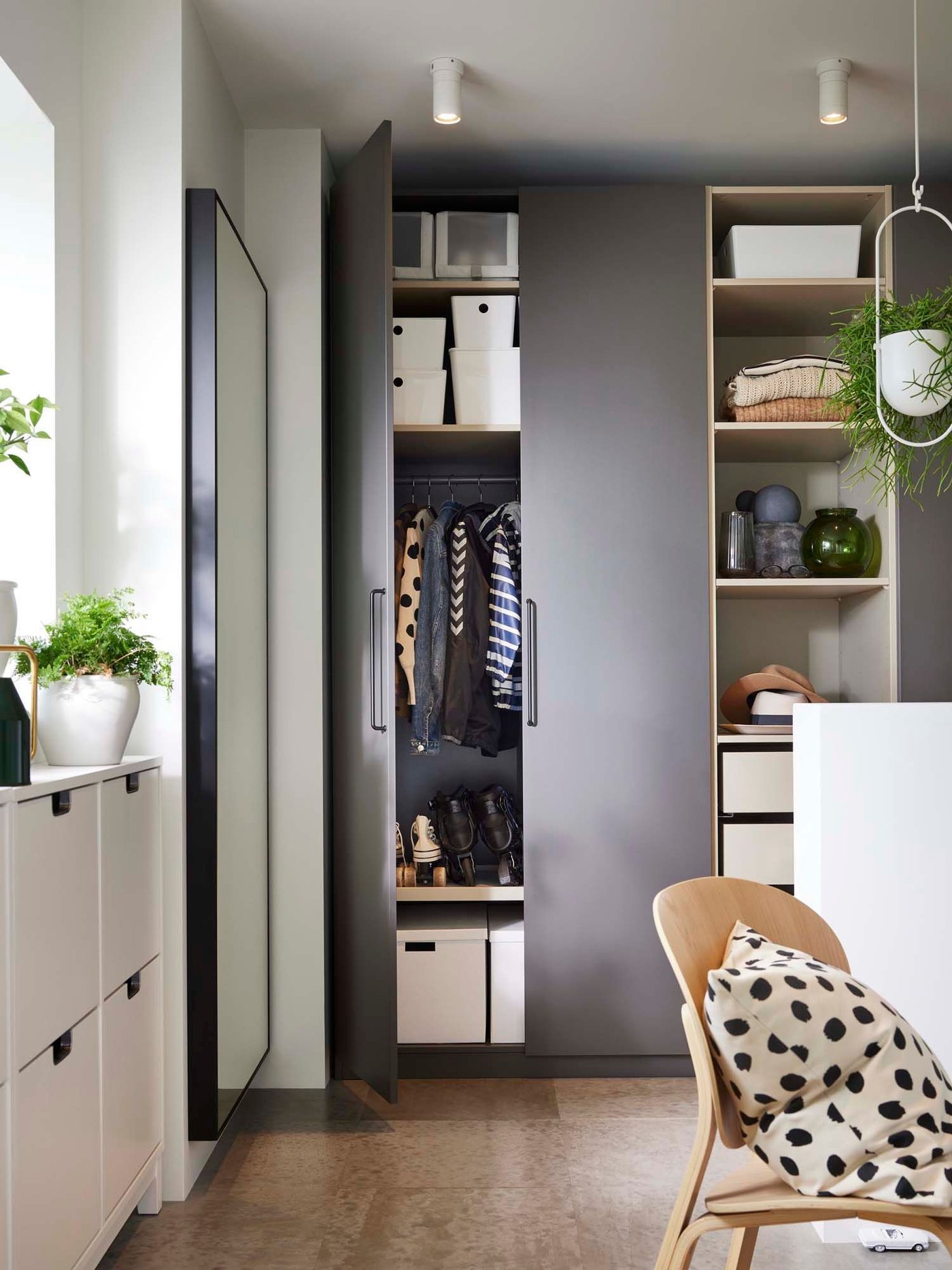 A hallway with grey storage cupboards. Below the window are white storage units for shoes.