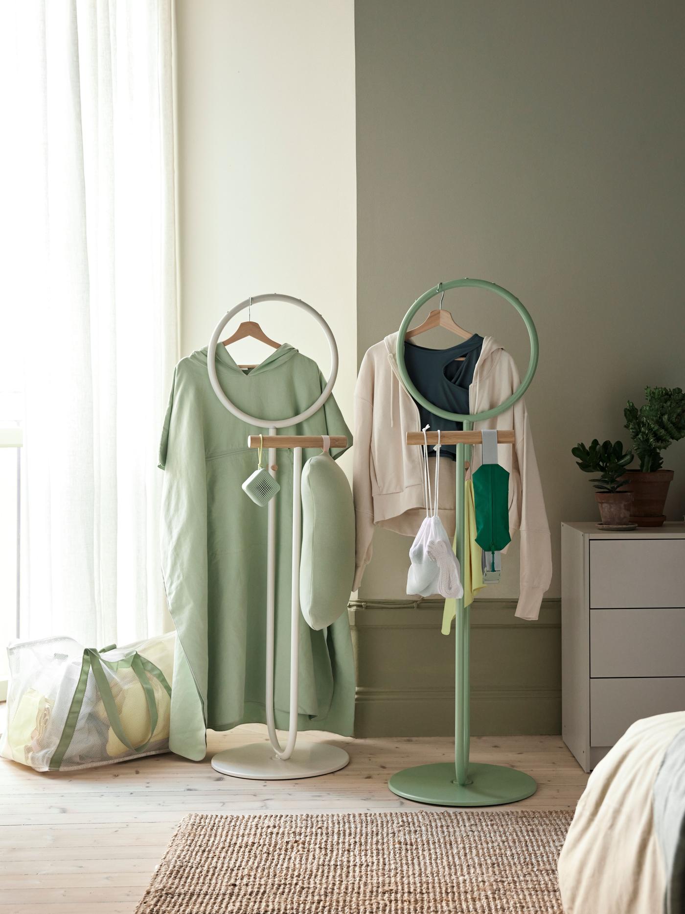 Clothing on wardrobe stands in a room with pale green walls.