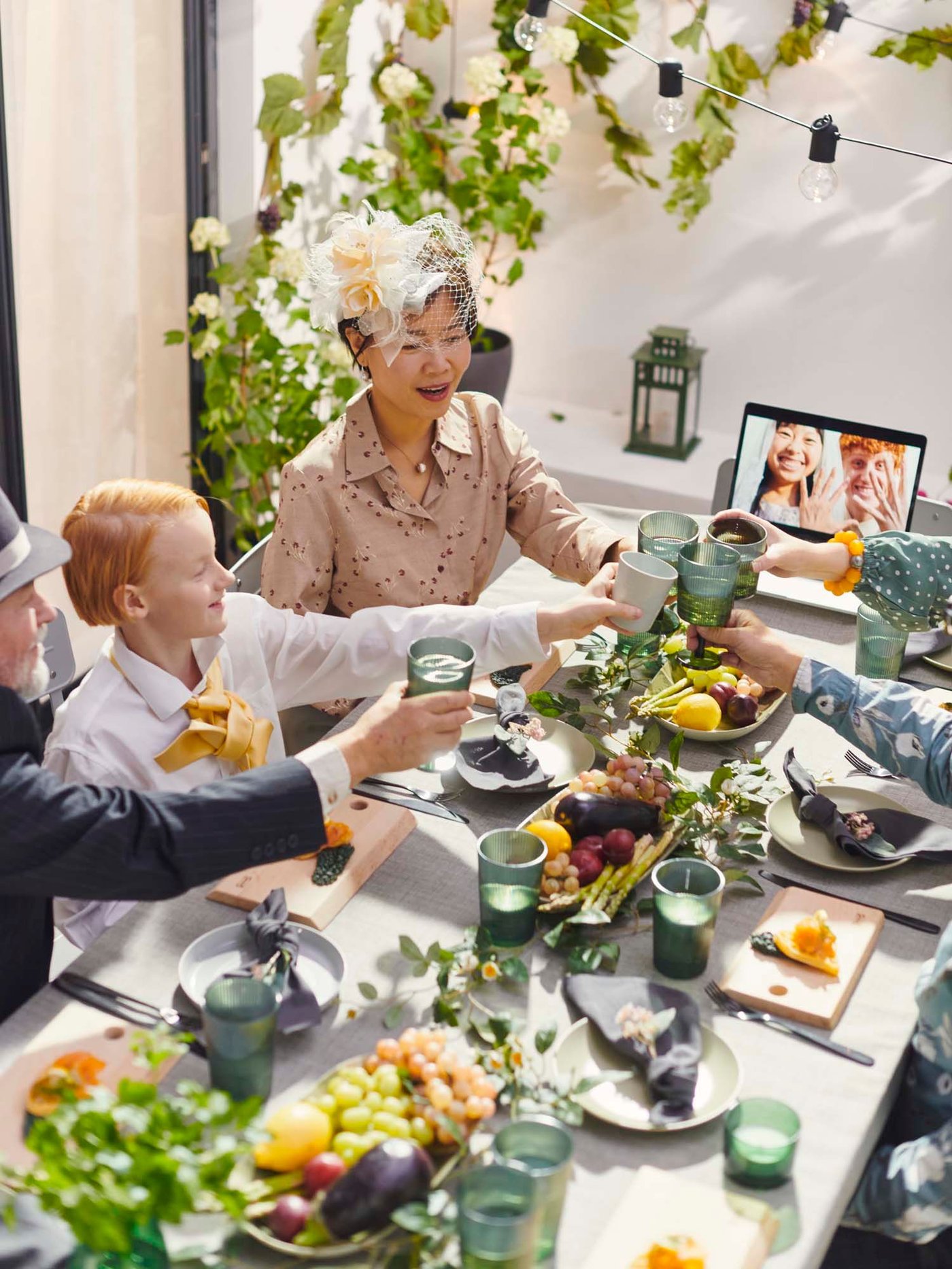 People sitting around a long table filled with snack platters and drinks in green plastic KALLSINNIG glassware.