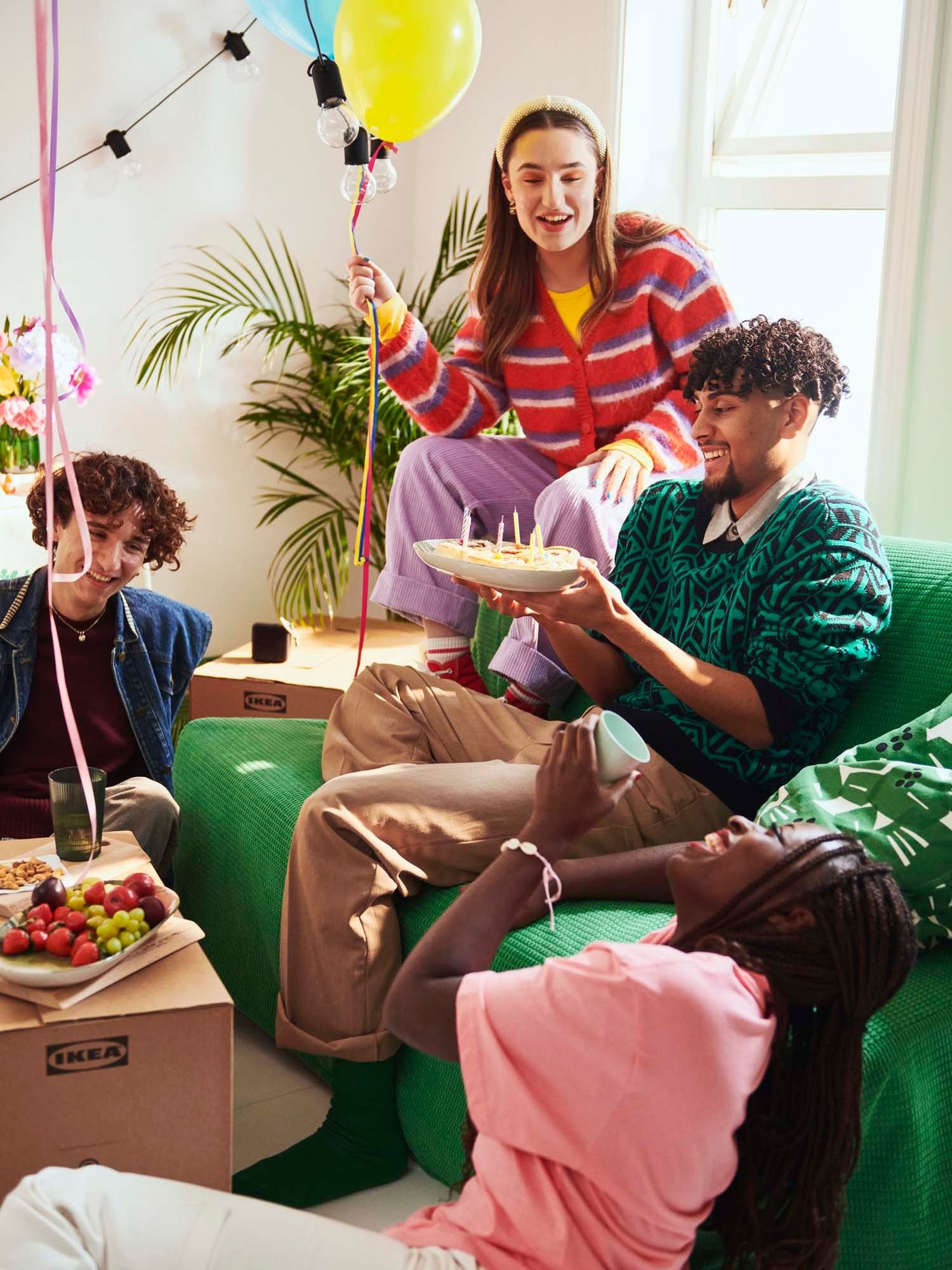 A group of four people sitting in a living area on and around a Vansbro bright green LYCKSELE LÖVÅS 2-seat sofa-bed. 
