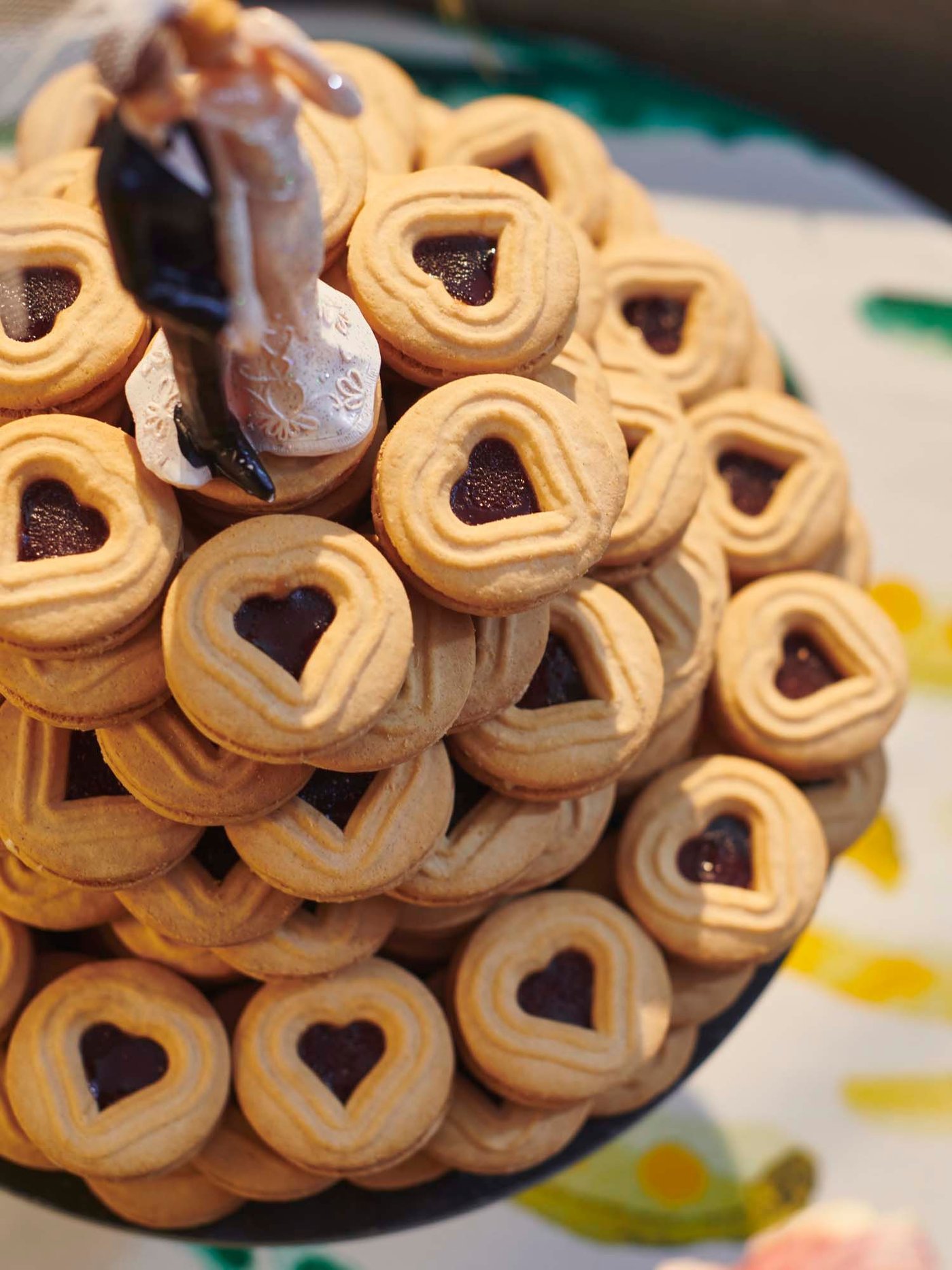 An overhead shot of a bride and groom cake topper on a tower of KAFFEREP biscuits with raspberry-flavoured filling.
