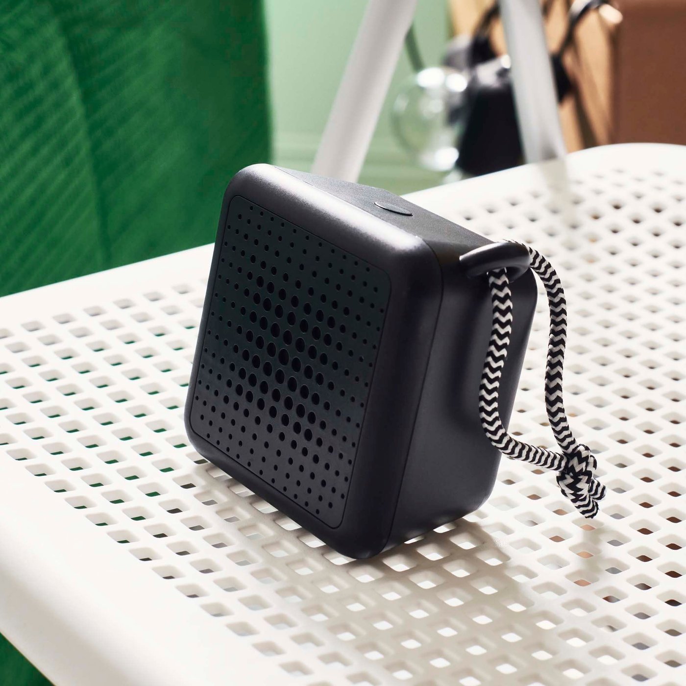 A waterproof/black VAPPEBY portable bluetooth speaker on the seat of a white/grey in/outdoor foldable TORPARÖ chair.