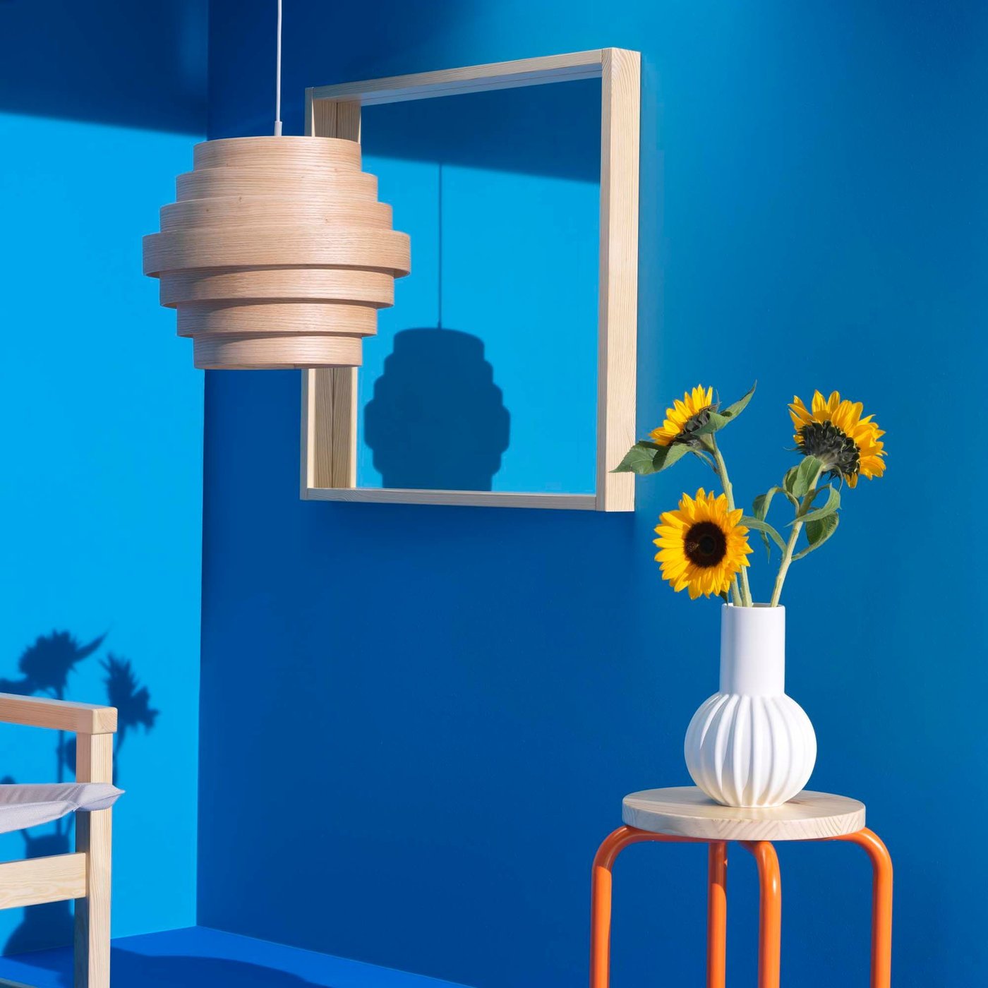 A blue roomset corner with a chair, pendant lamp, stool and mirror.