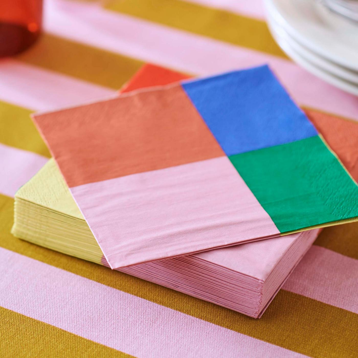 A closeup of a pack of TESAMMANS paper napkins atop TESAMMANS pre-cut fabric.