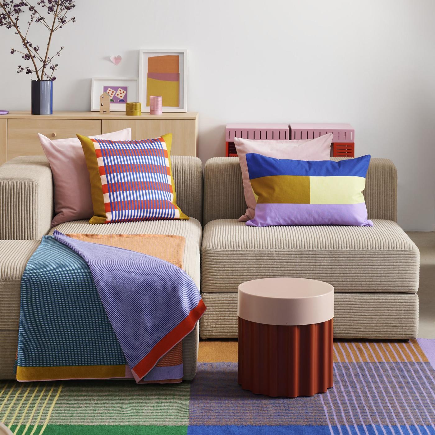 Colourful textiles, decorations and furniture next to each other on a beige sofa standing on a patterned couch. A collection of colourful products!