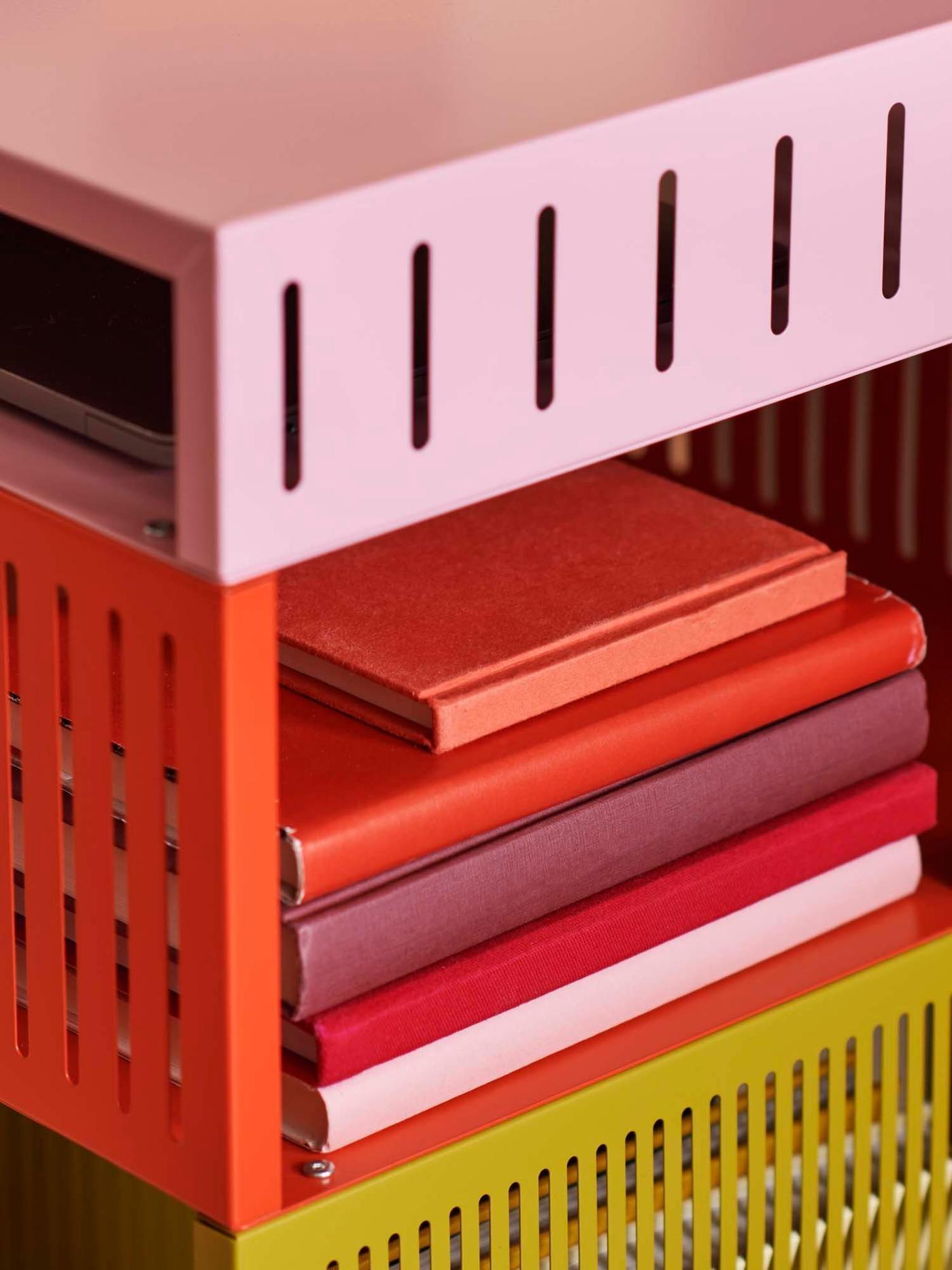 A closeup of a TESAMMANS storage unit on castors with a pile of red books on one shelf.