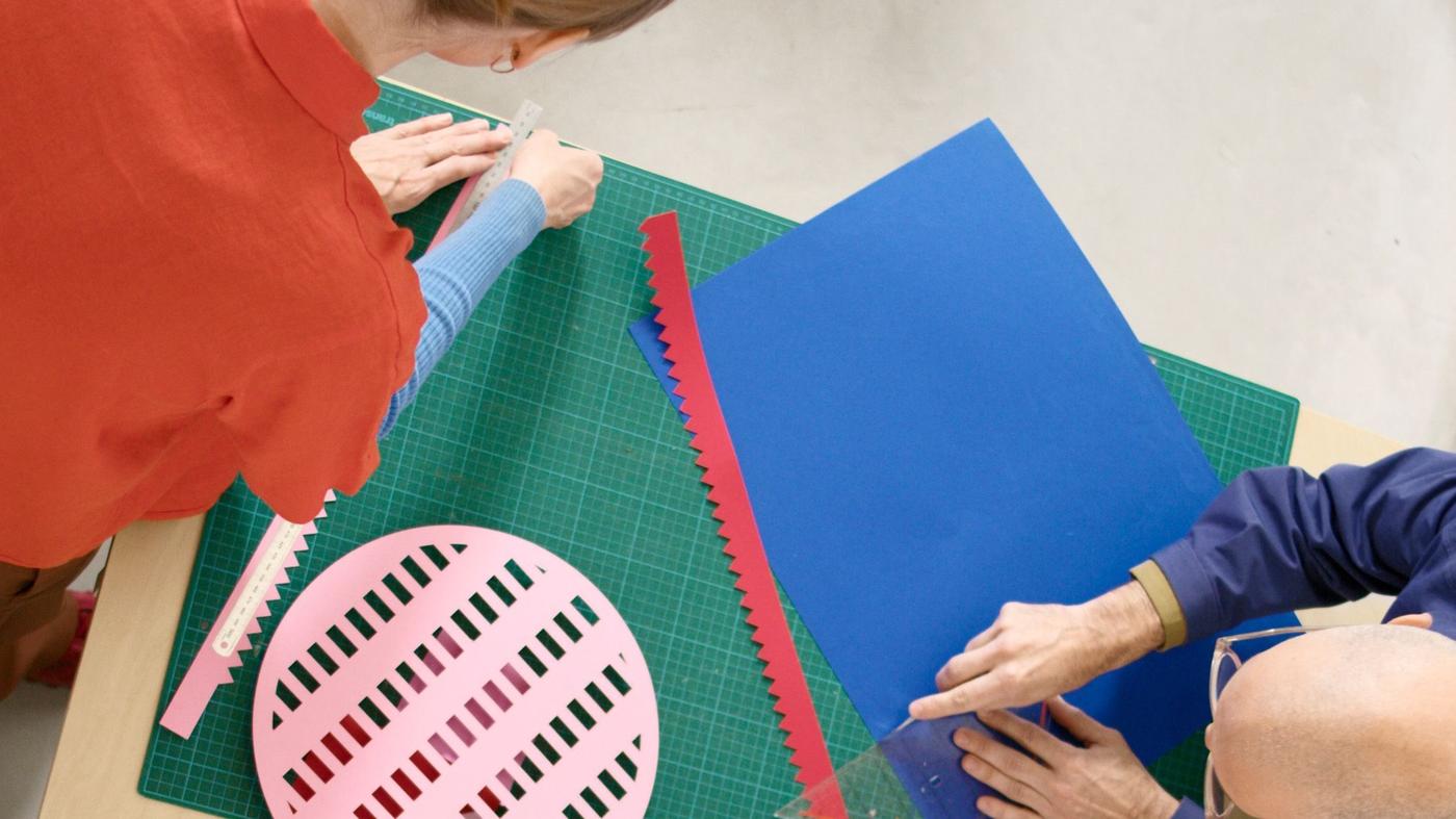 Two people cutting and creating colourful paper prototypes of the TESAMMANS collection.