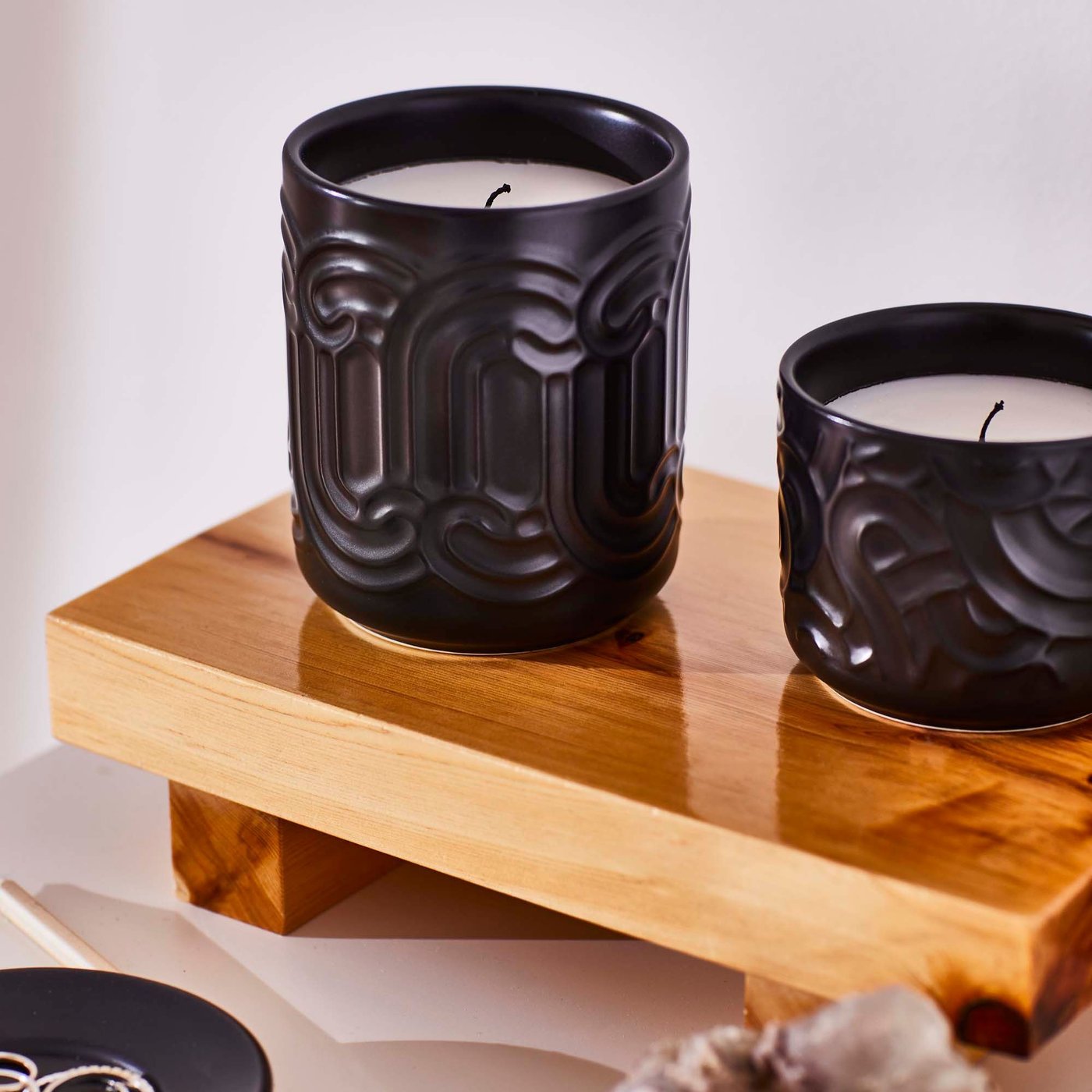 Two black candles are placed on a copper coloured plinth.