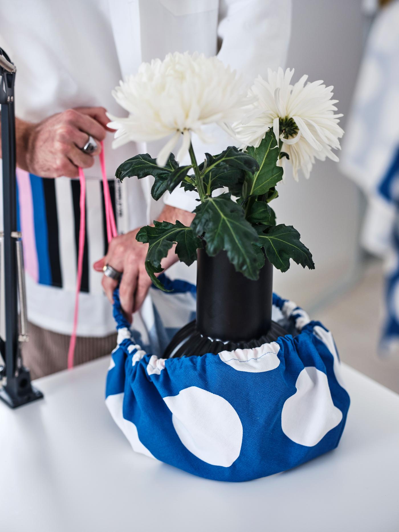 A person is using a piece of fabric to wrap the plant.