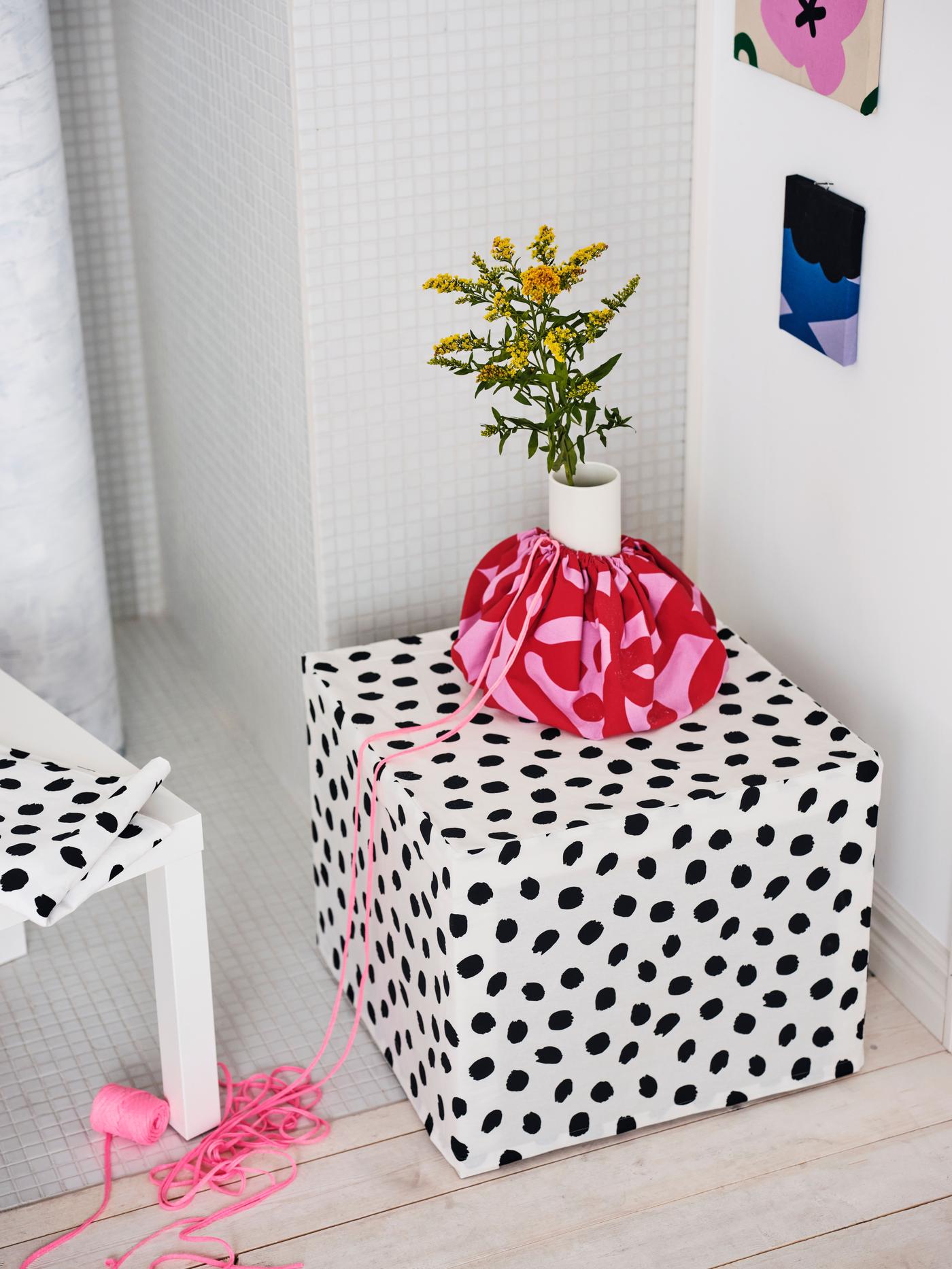 A square box covered with white fabric with black dots.