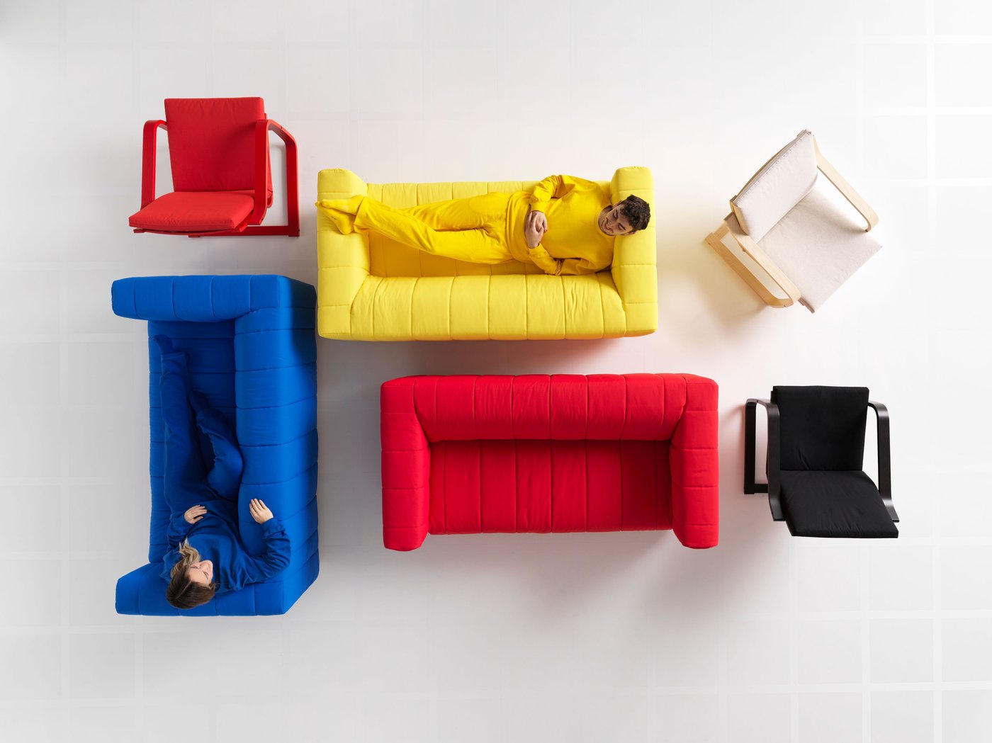 Seen from above, blue, red and white KLIPPAN sofas stand next to a red, black and white POÄNG chair.